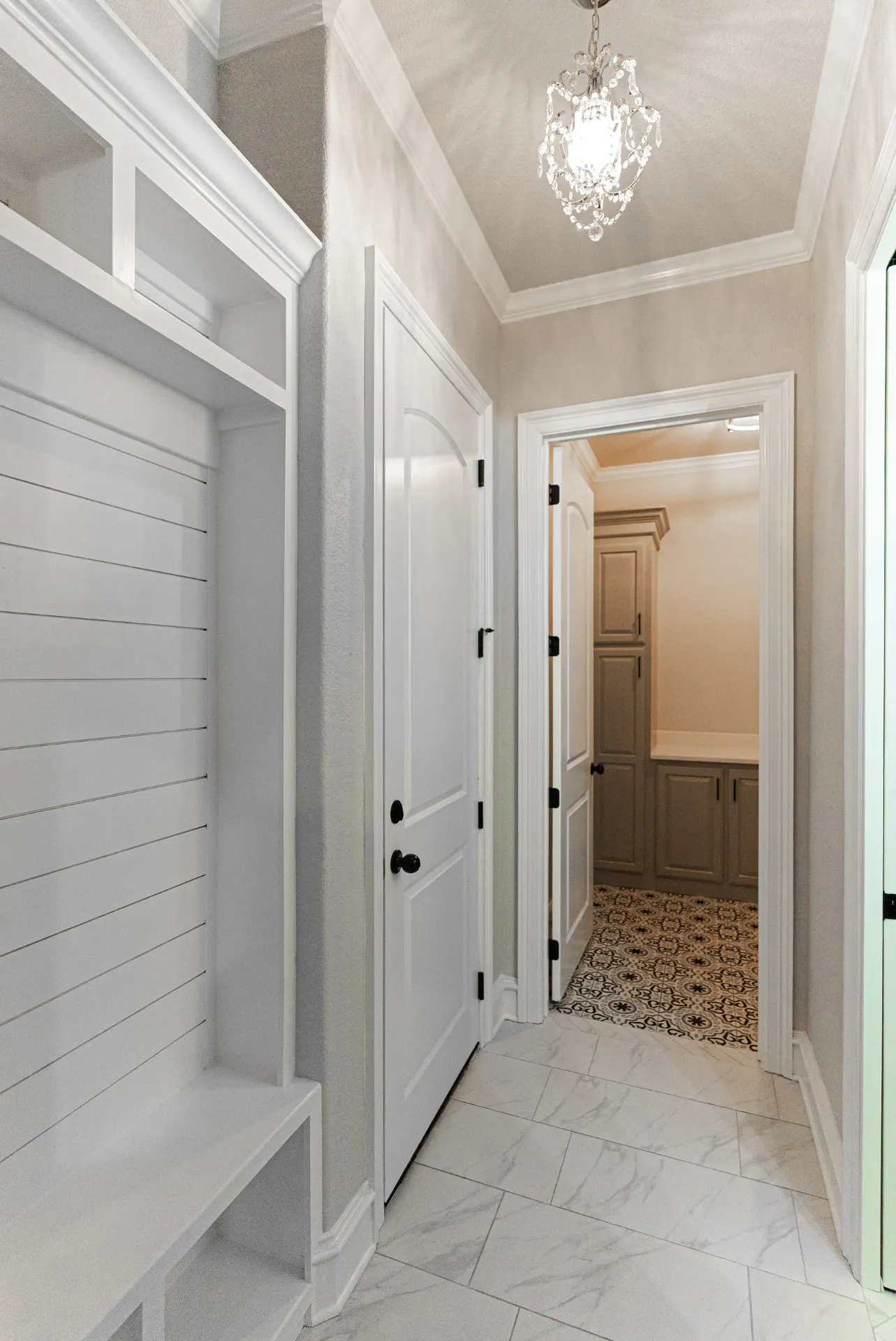 Hallway at 1511 NW 12th St with shiplap built-ins, crystal chandelier and patterned-tile bath beyond