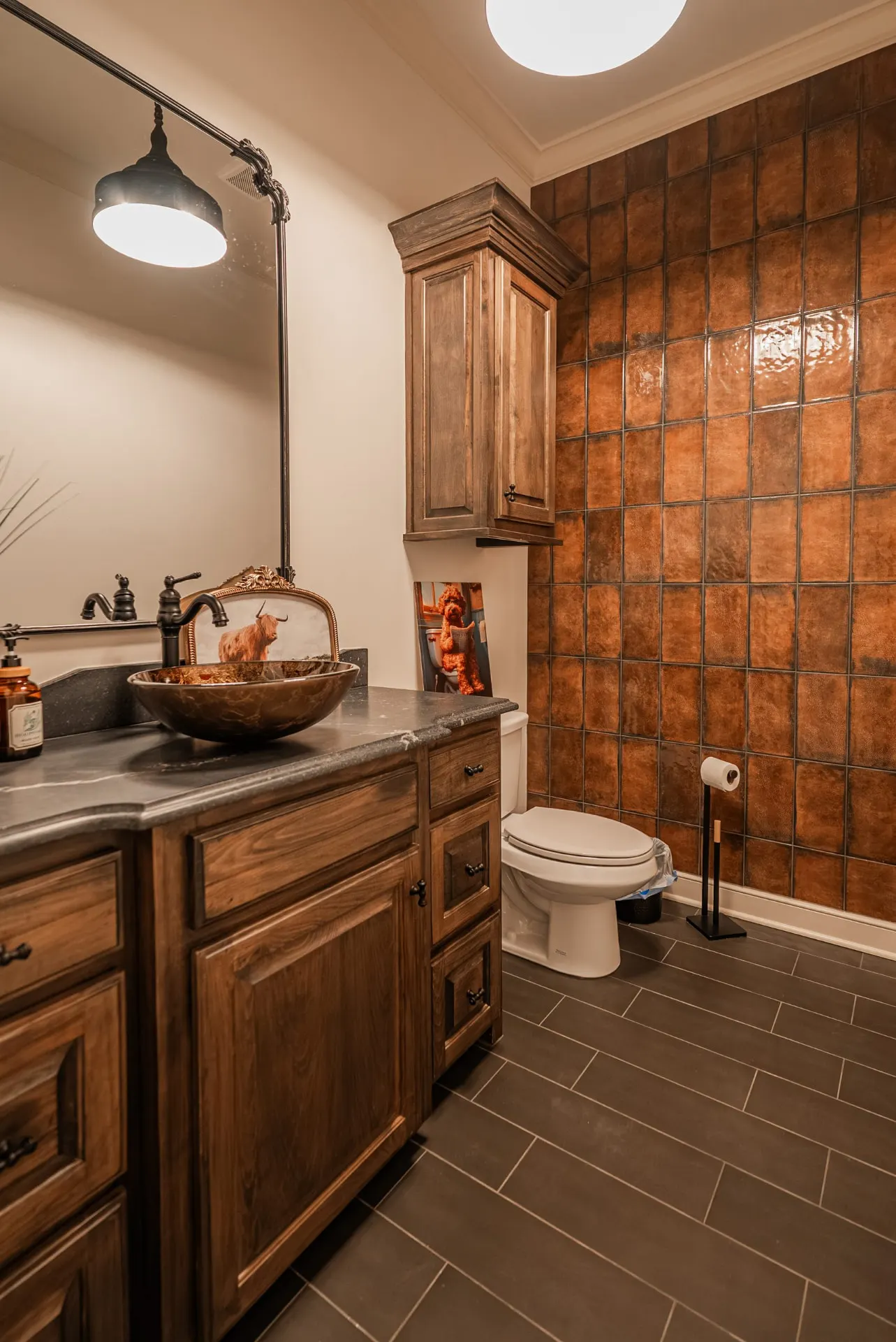 Powder room at 1610 NW Eliam Dr with copper-toned tile accent wall and an amber glass vessel sink