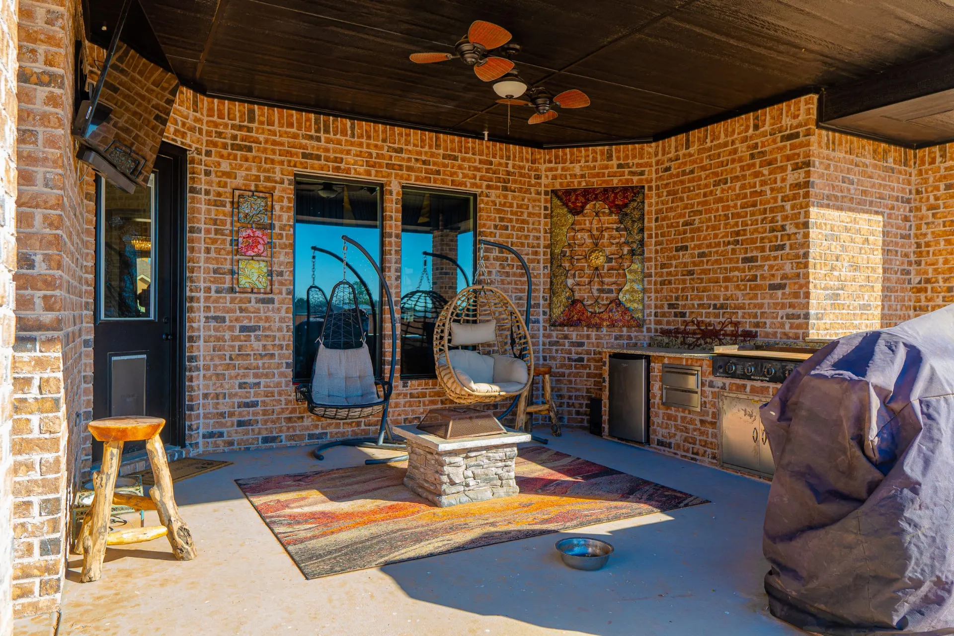 Alternate view of the covered outdoor kitchen and fire-pit seating area in red brick at 8821 Shawn Dr