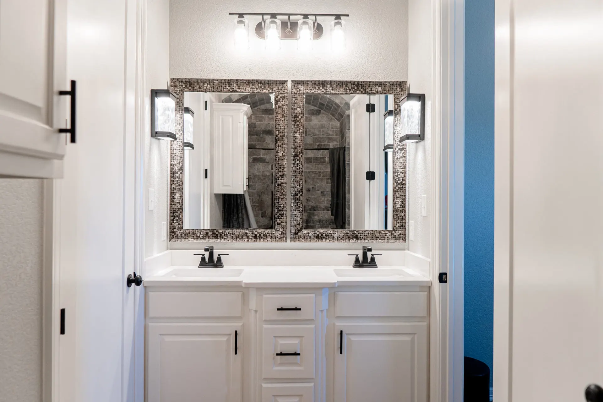 Bath at 8821 Shawn Dr with a white double vanity, matte black hardware, dual undermount sinks and twin mosaic-framed mirrors