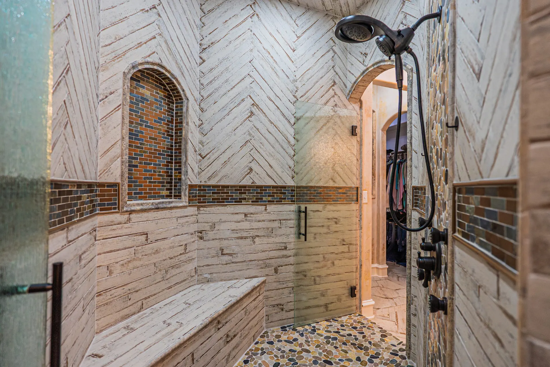 Walk-in shower at 5 Prairie Ln with whitewashed herringbone tile and river-rock floor