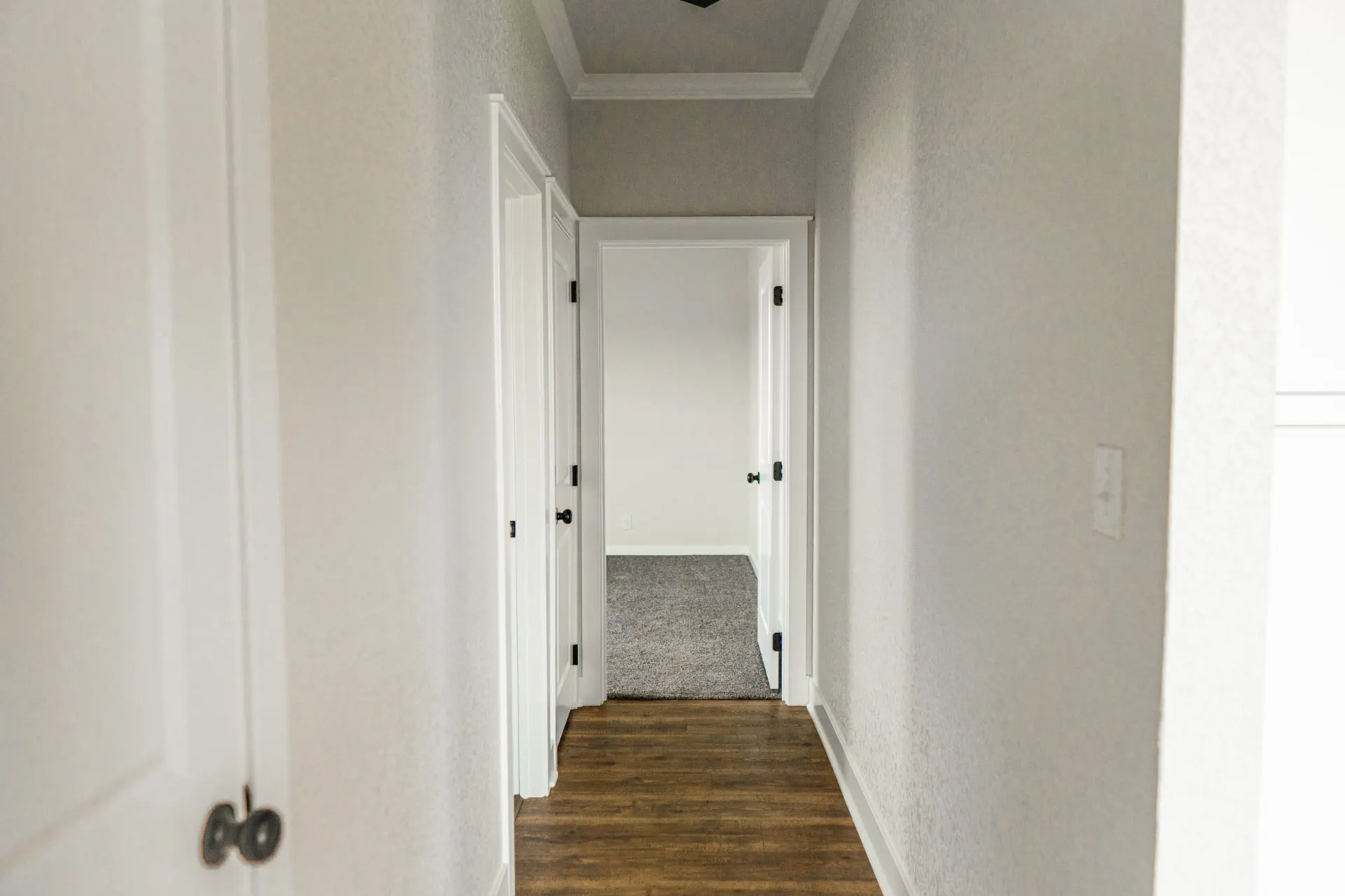 Hallway at 1615 NW 12th St opening to a carpeted bedroom with wood-look floors and crisp white trim