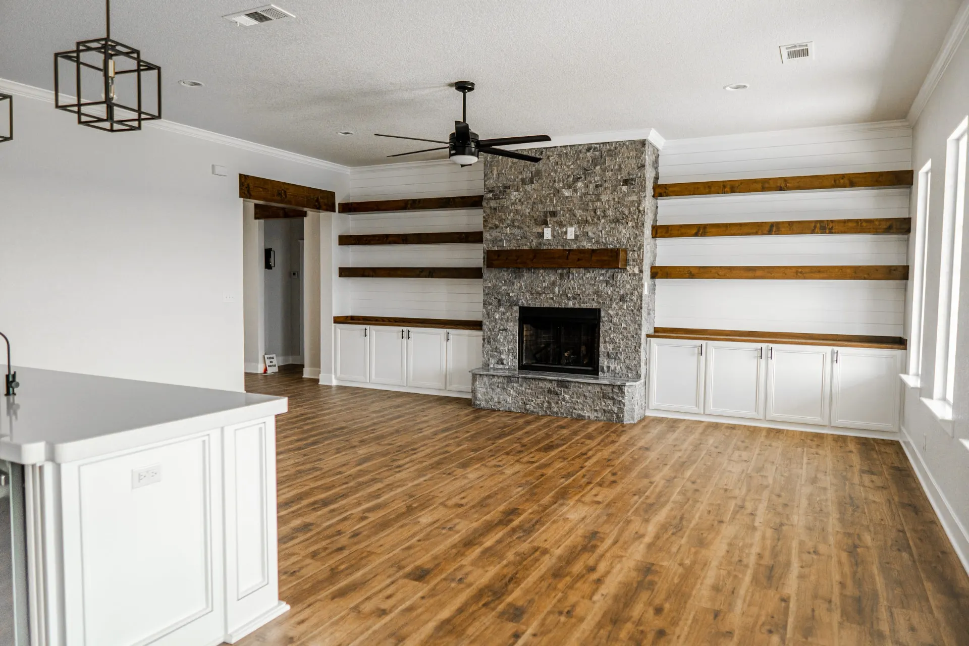 Great room at 1615 NW 12th St with floor-to-ceiling stacked-stone fireplace, floating wood shelves and white shiplap