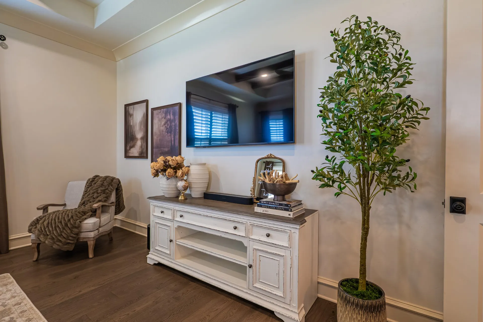 Media area at 1610 NW Eliam Dr with a wall-mounted screen over a distressed console and an upholstered armchair