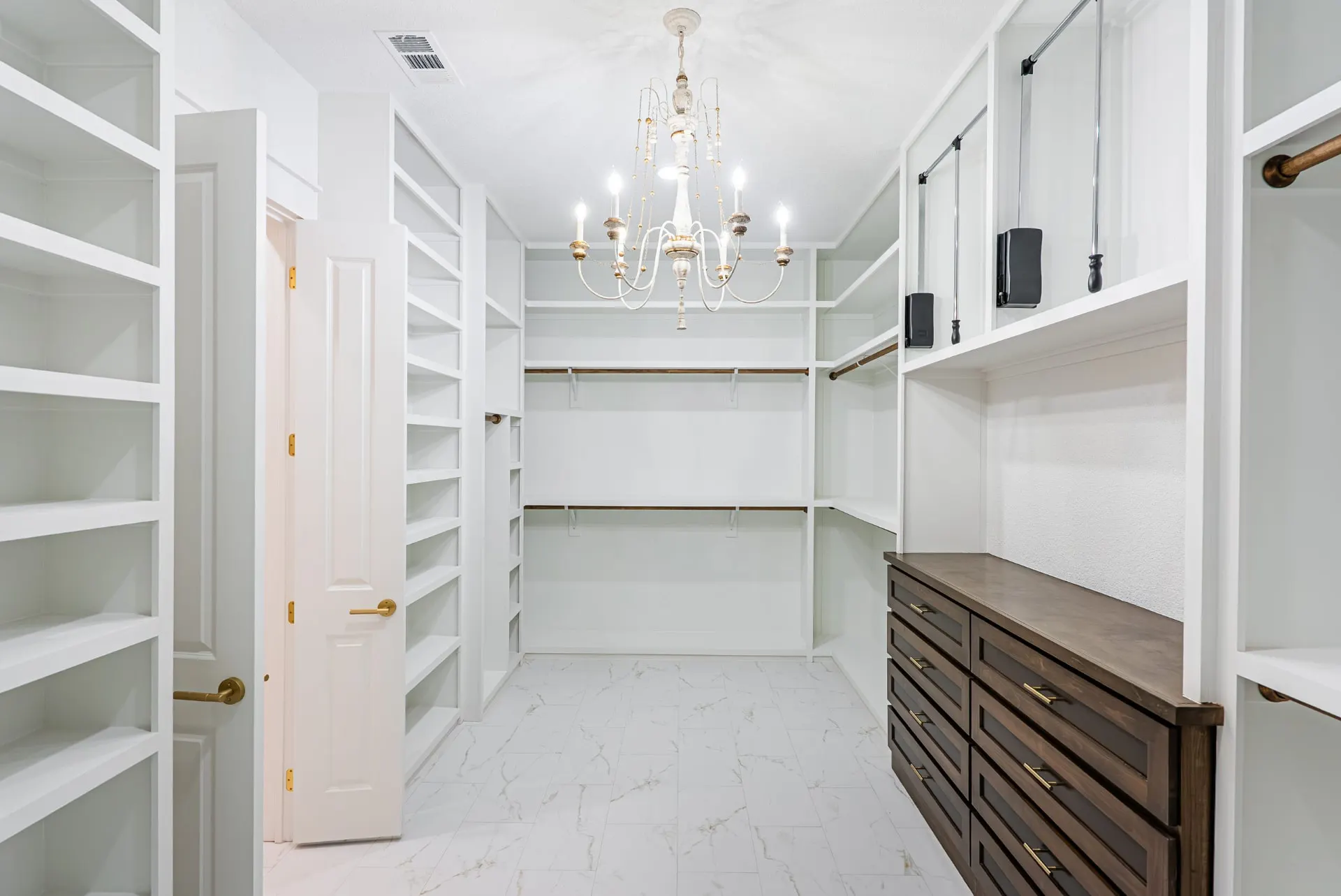 Walk-in closet with marble-look tile, white built-ins and a crystal chandelier at 1607 NW 12th St