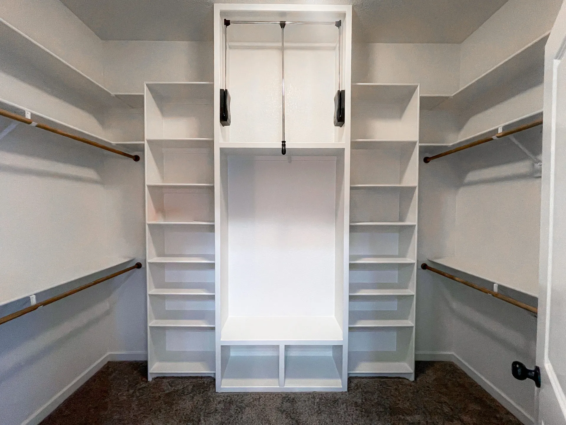 Walk-in closet at 1615 NW 12th St with white built-ins, twin hanging rods, center tower and seat