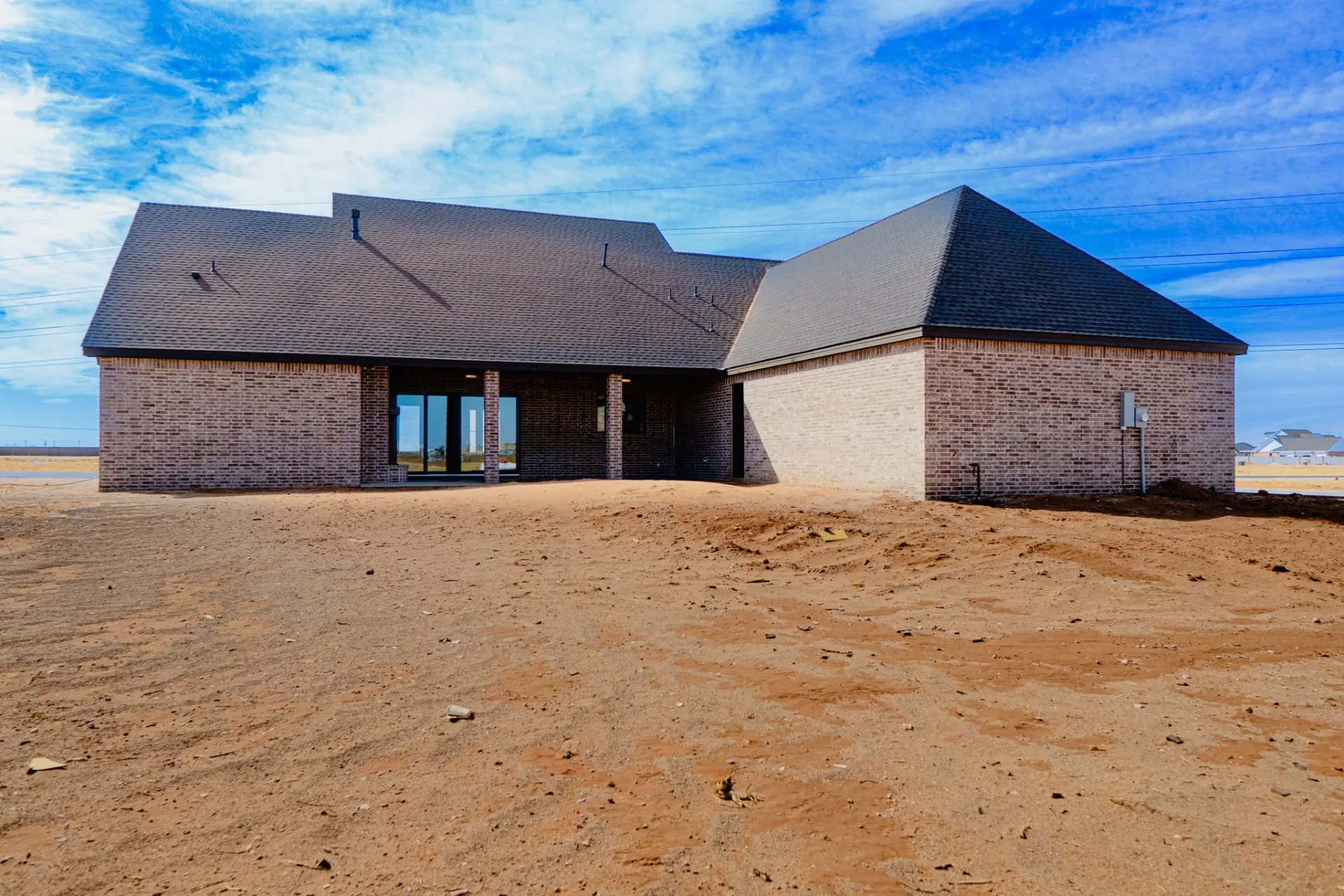 Rear elevation of the 12th St Home in brick with a hipped roof and a covered patio with glass doors