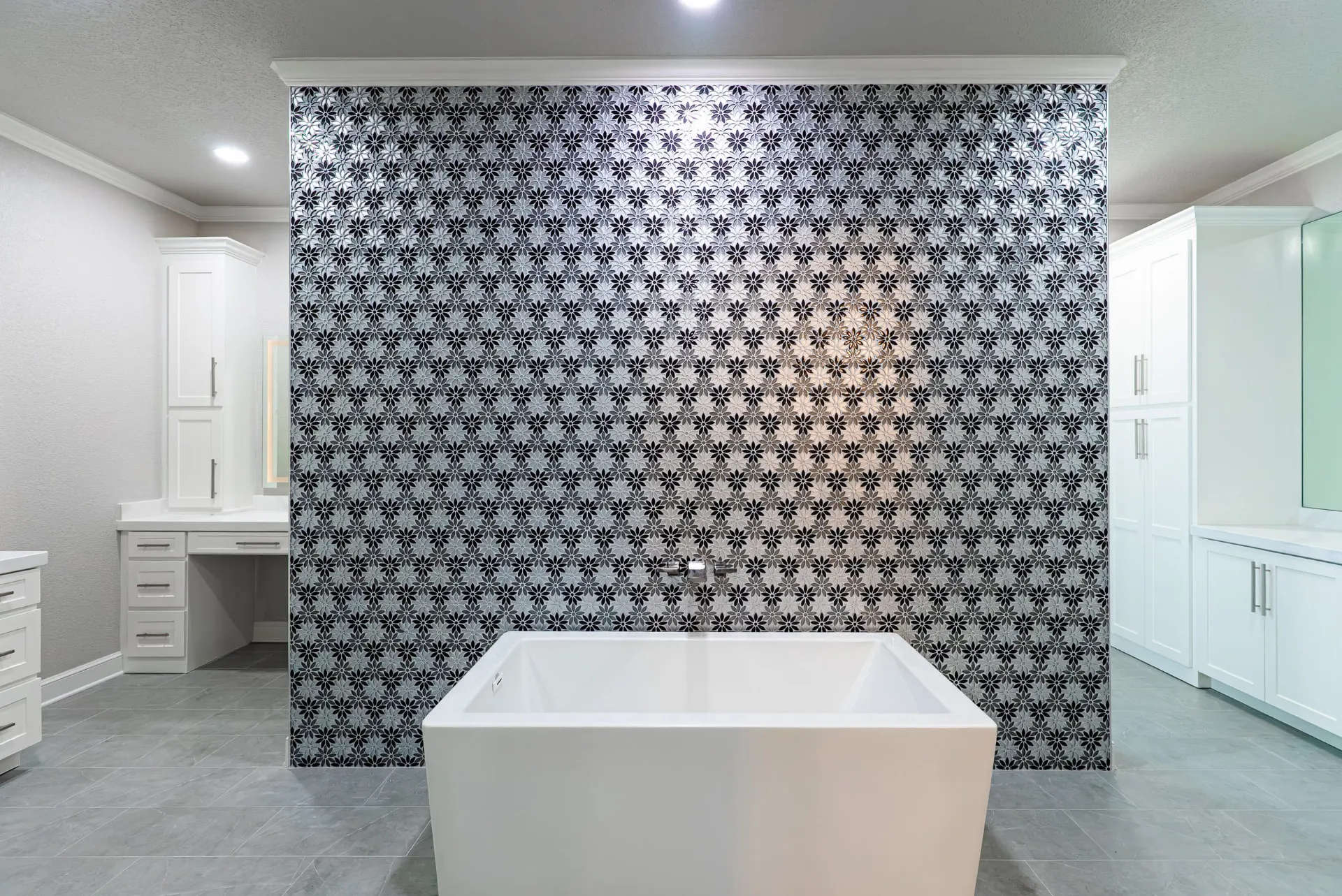 Freestanding tub before a black-and-white floral mosaic feature wall in the primary bath at 27 Santiago Mission Dr