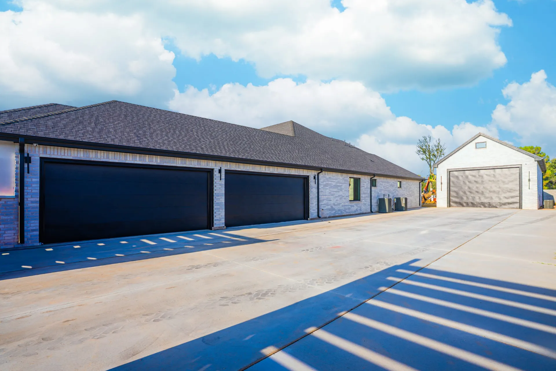 Side approach at 27 Santiago Mission Dr with dark garage doors, light brick walls and poured concrete flatwork