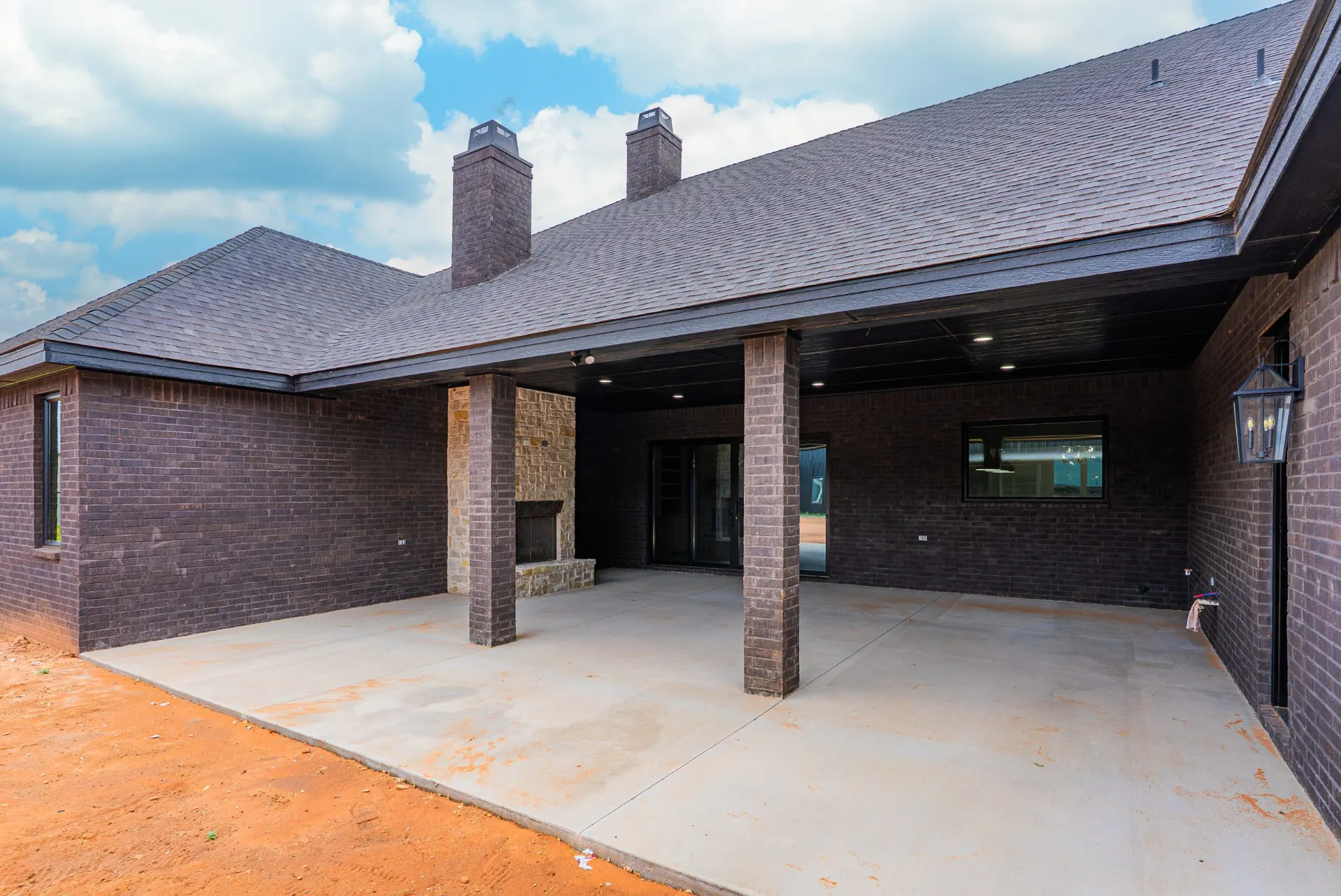 Covered back patio at 1607 NW 12th St with a stone outdoor fireplace and brick columns