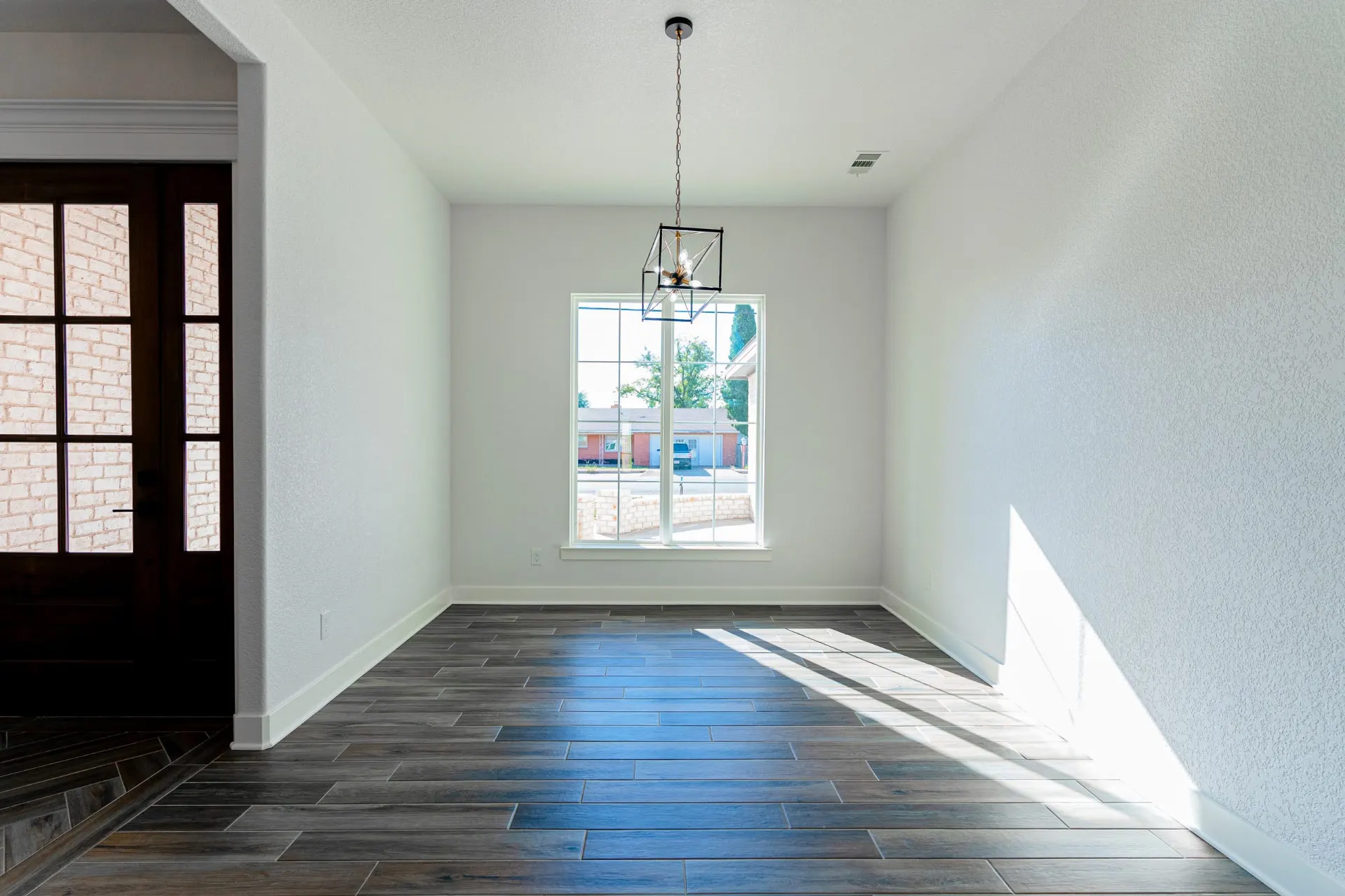 Front dining room at 718 K Ave with straight-laid wood-look floors, a black lantern pendant and a large white-framed grid window