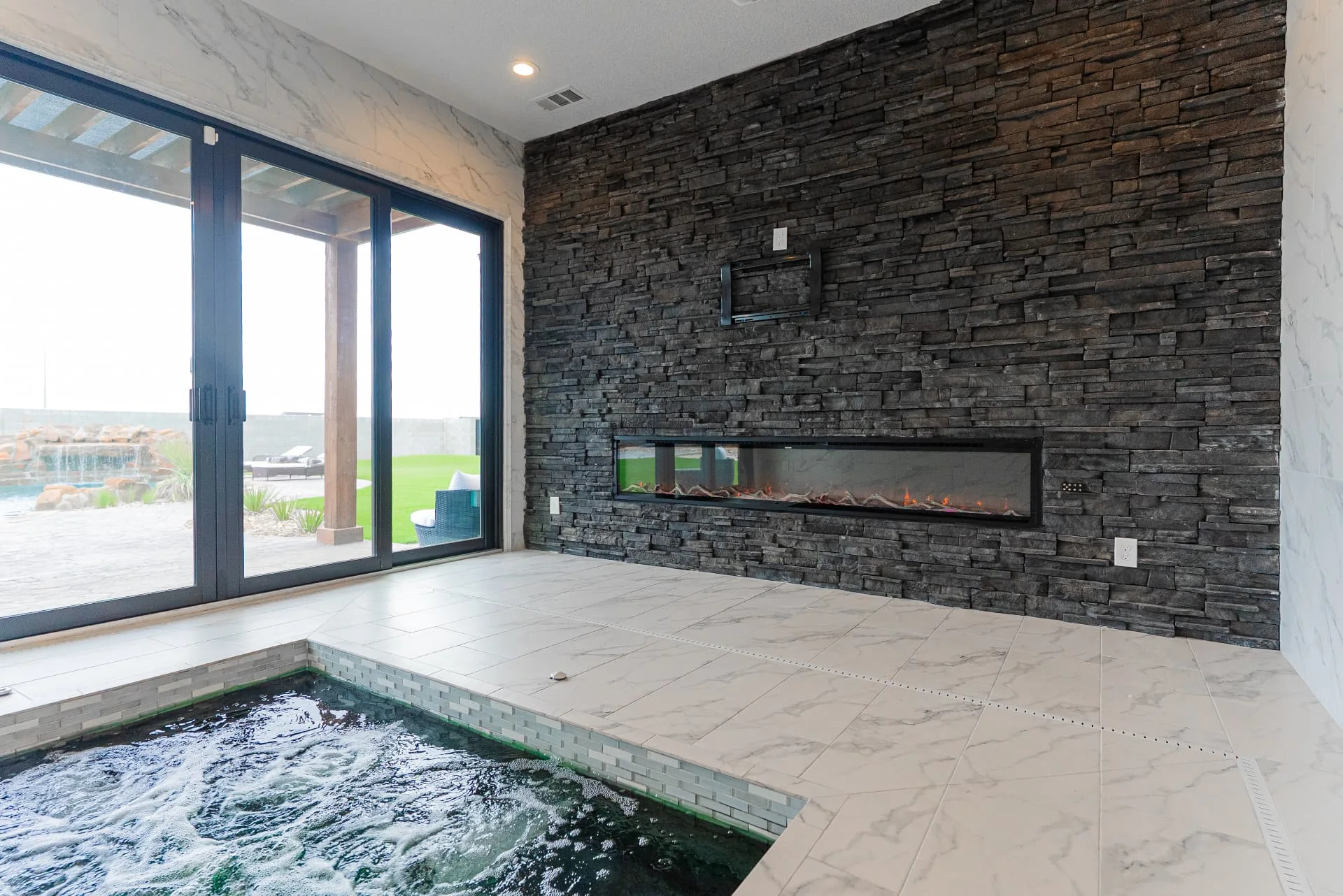Indoor spa and dark stone fireplace wall at The Flores Estate