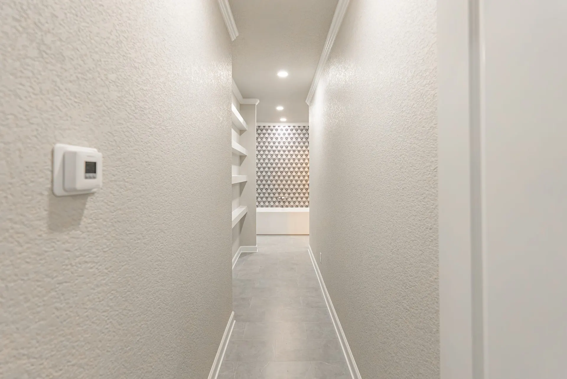 Hallway leading to the primary bath's floral mosaic tub wall at 27 Santiago Mission Dr