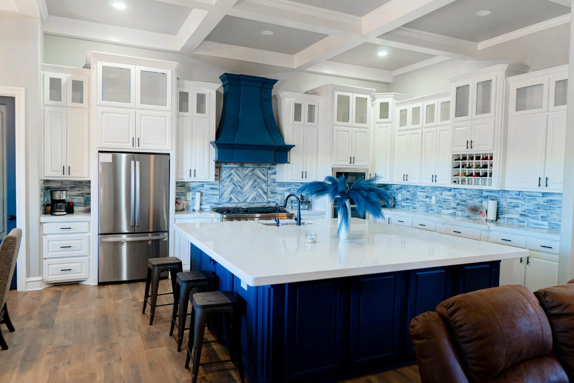 Kitchen at 8821 Shawn Dr with a navy island under a white quartz top, a navy range hood, white glass-front cabinetry, a blue herringbone backsplash and a coffered ceiling