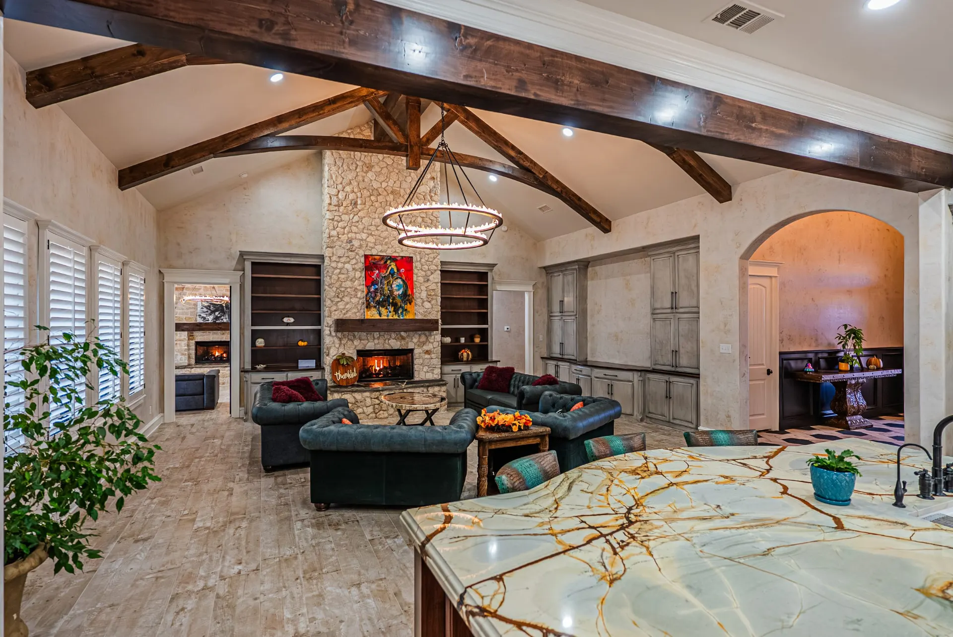 Great room at 5 Prairie Ln seen from the quartzite island with dual ring chandelier