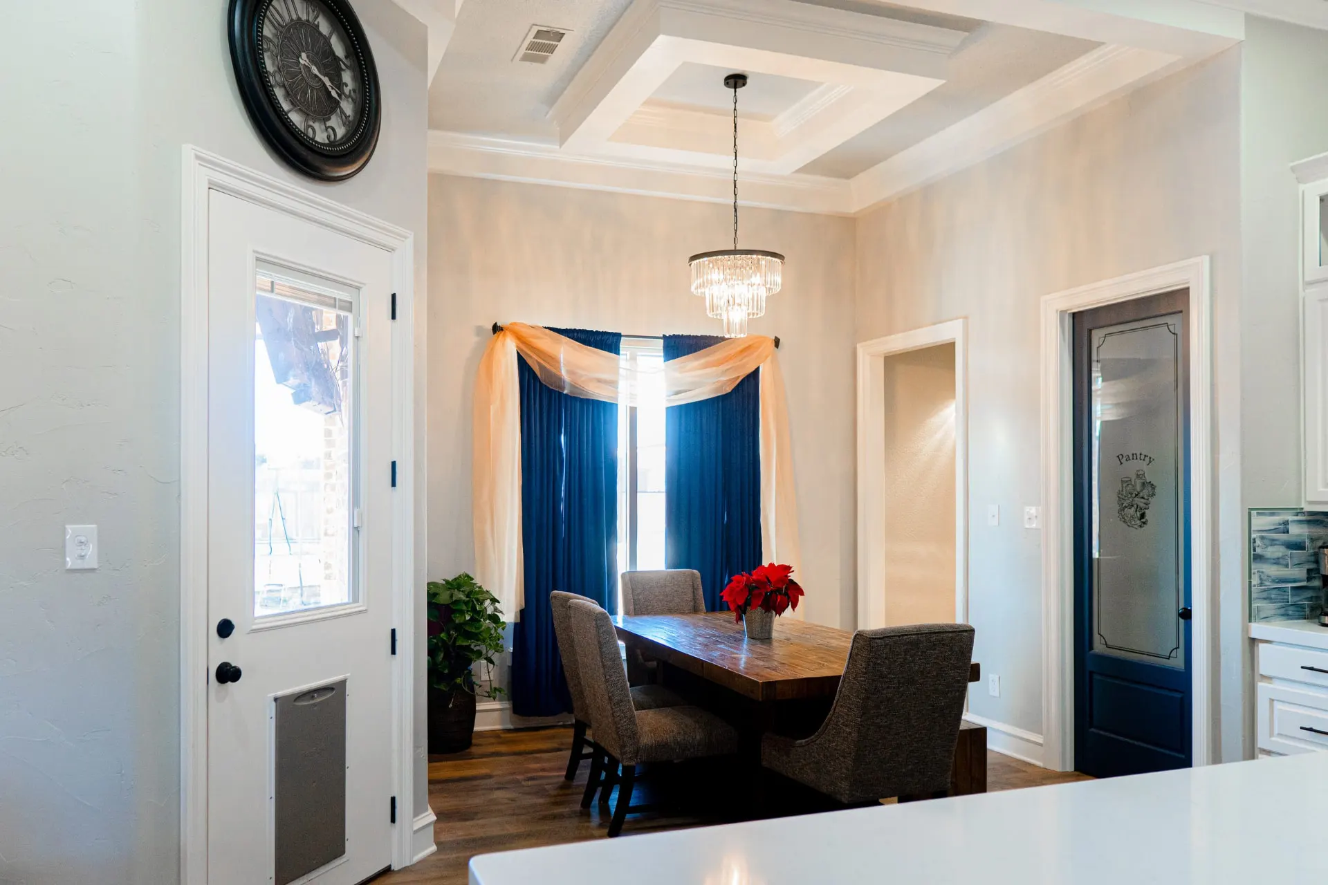 Breakfast nook at 8821 Shawn Dr with a wood table and upholstered chairs under a crystal chandelier, a decorative tray ceiling and an etched-glass pantry door