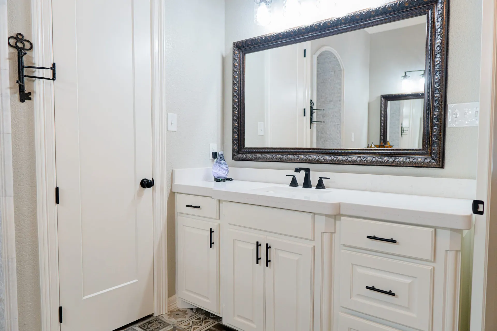 Second primary vanity with white cabinetry, matte black faucet and a bronze ornate mirror at 8821 Shawn Dr