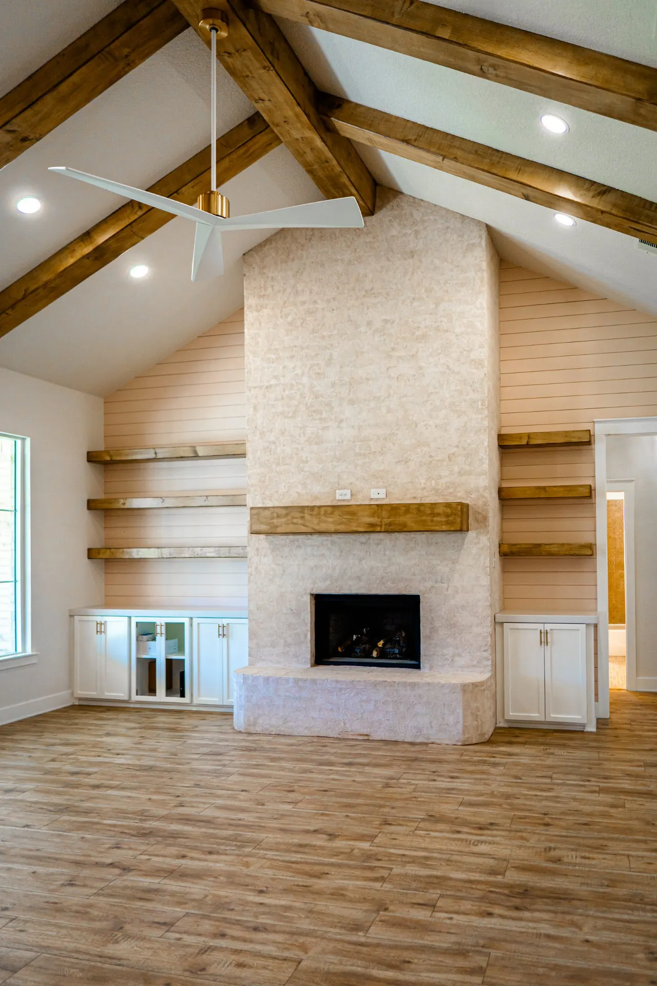 Tall view of the plastered fireplace tower and wood-blade ceiling fan beneath the beamed vault at Sarai Home