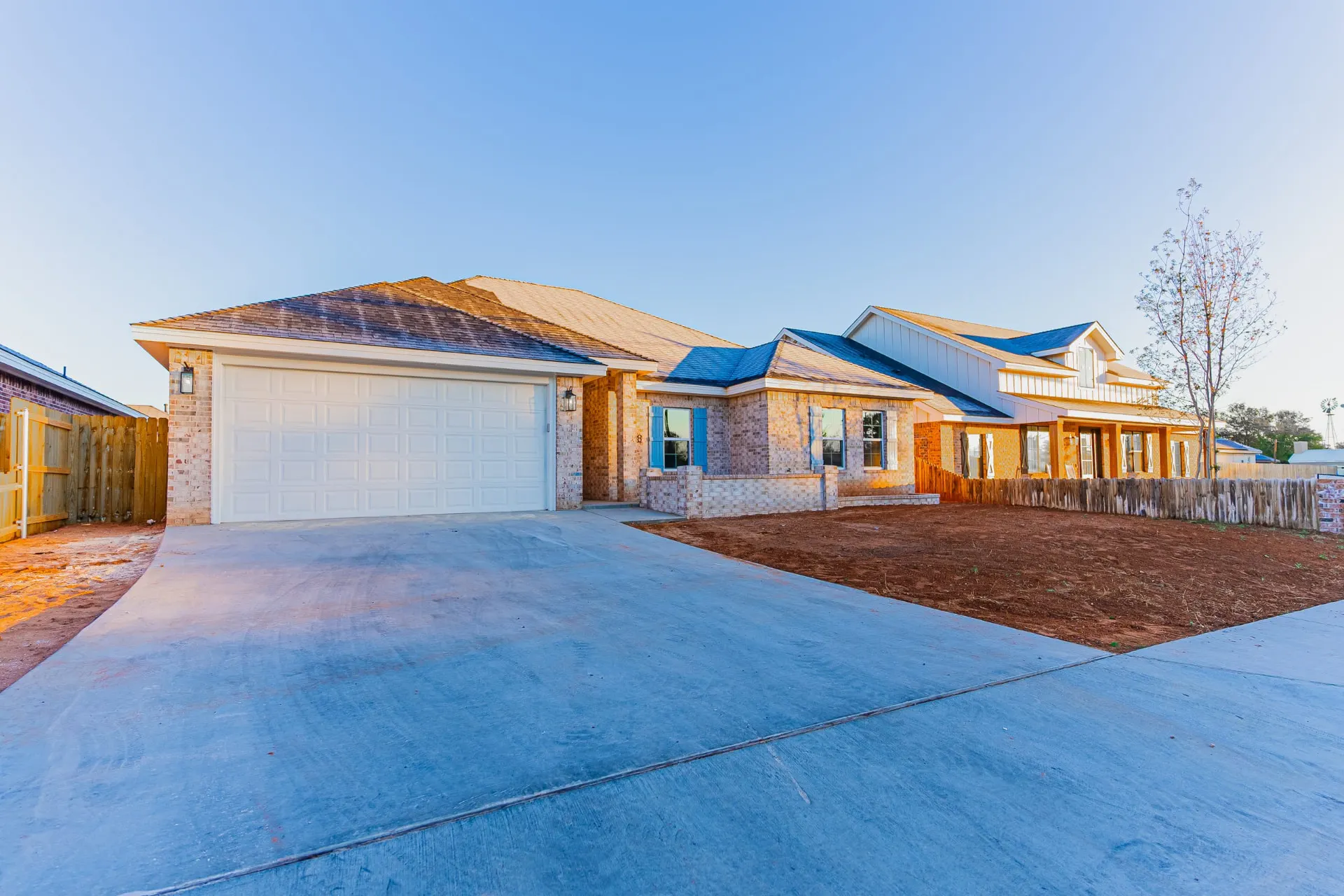 Second front view of 708 K Ave showing the brick facade, blue shutters, curved concrete drive and neighboring homes