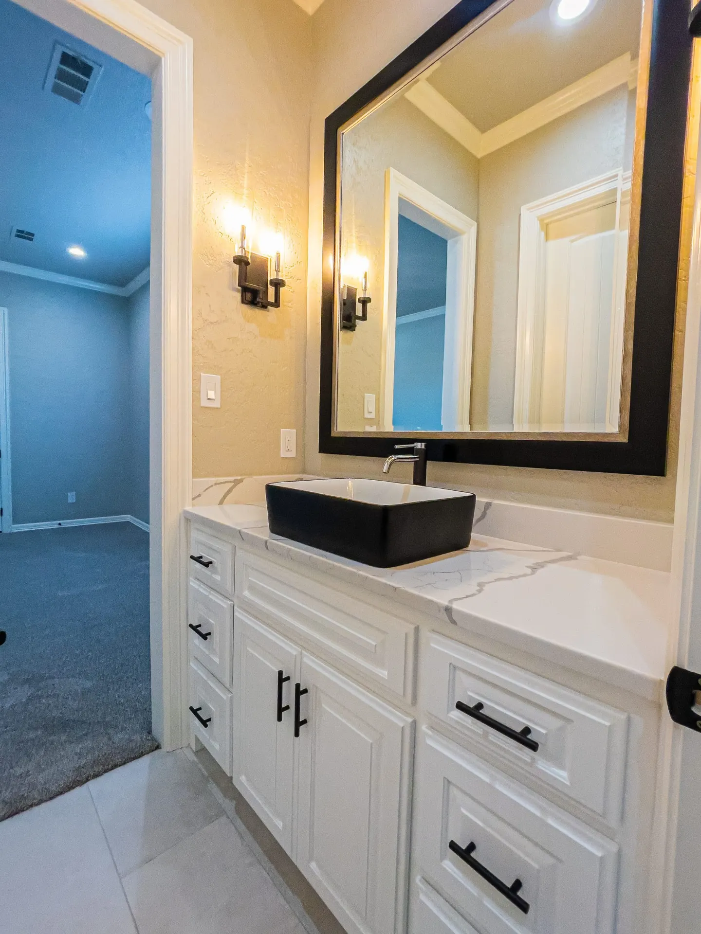 Guest vanity with white cabinetry, black vessel sink and framed mirror at 1501 NW 12th St