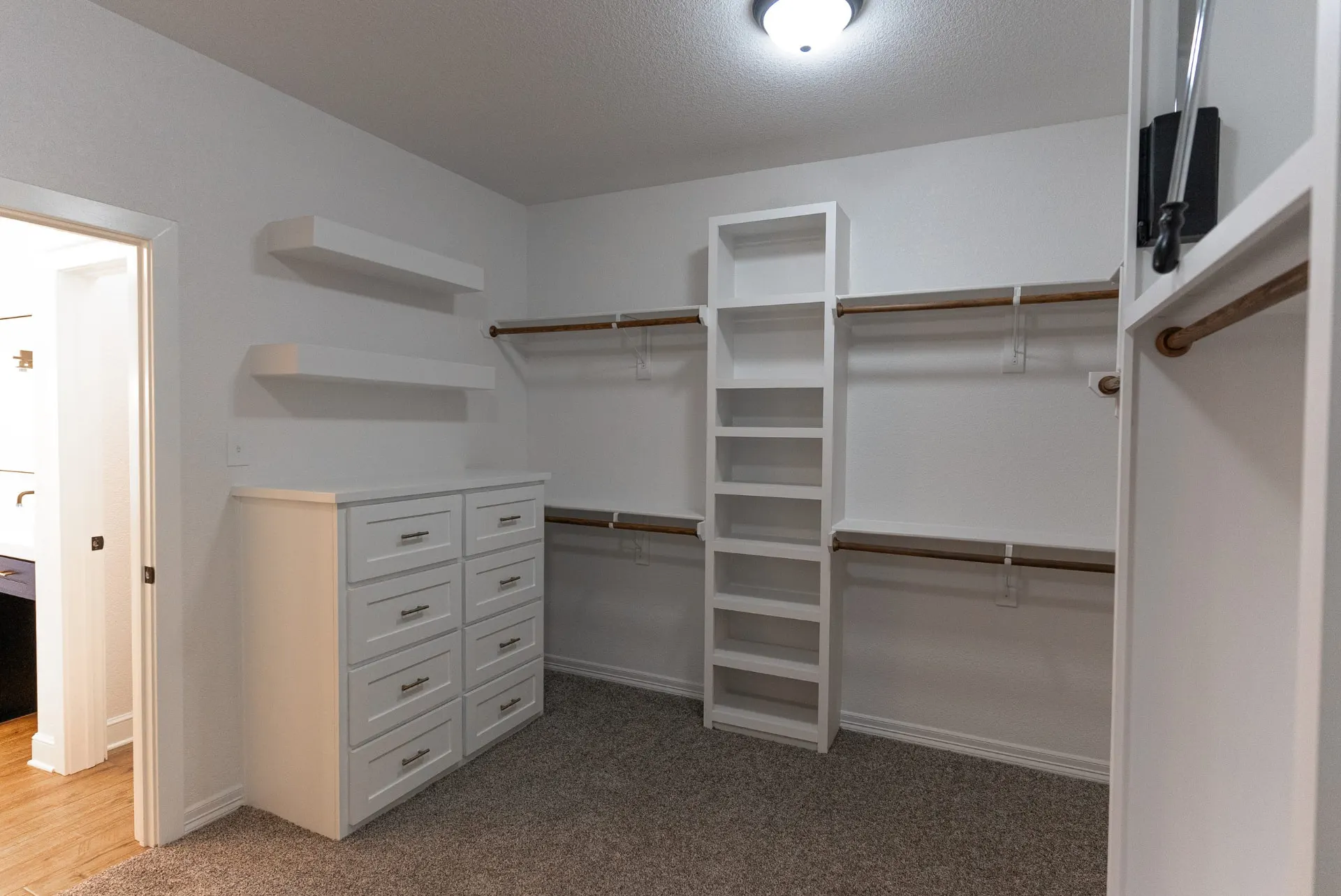 Walk-in closet at 718 K Ave with white built-ins, an eight-drawer dresser, floating shelves and a shoe tower