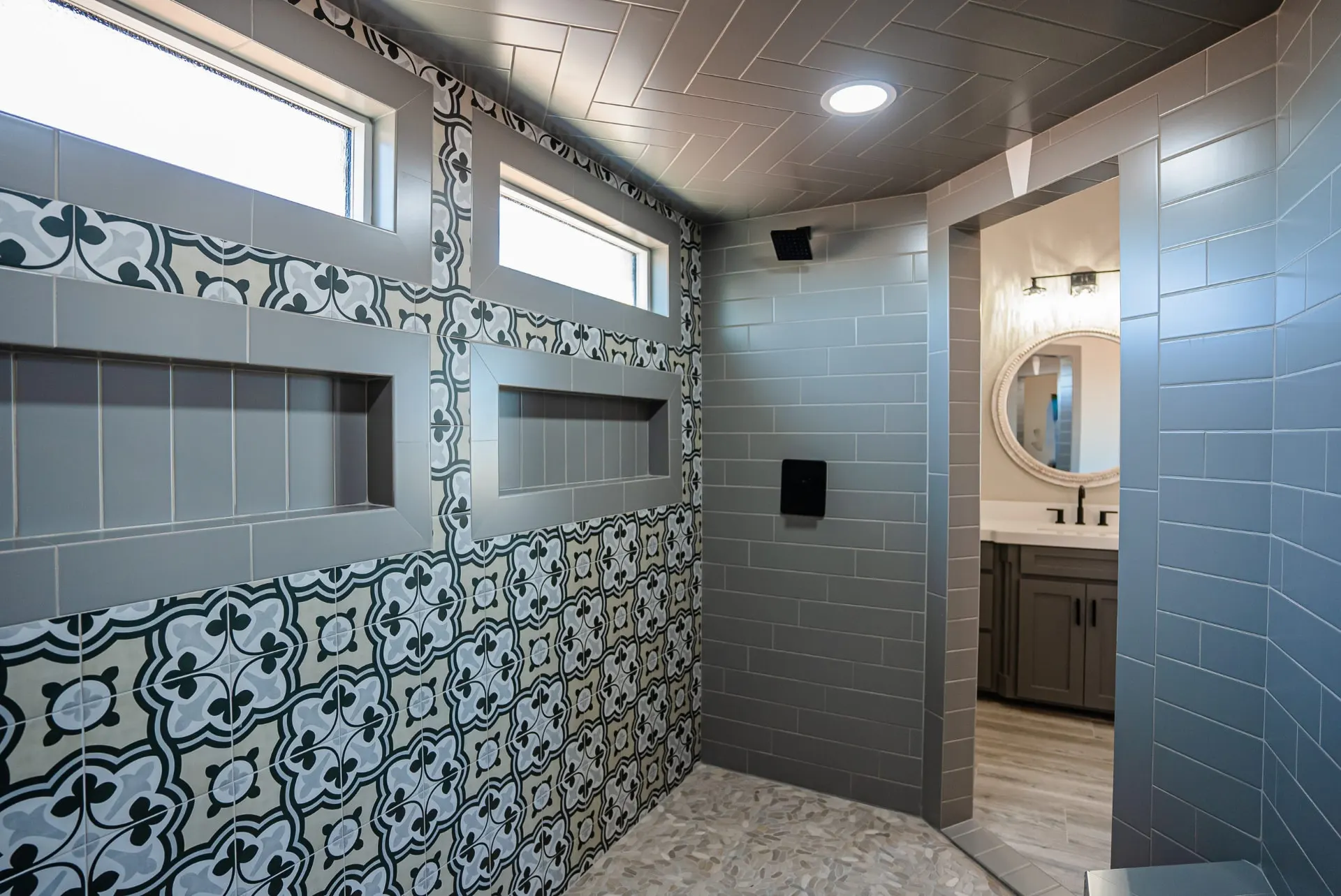 Walk-in shower at the Eliam St Home showing the patterned tile wall, herringbone ceiling, twin dormer windows and view to the vanity