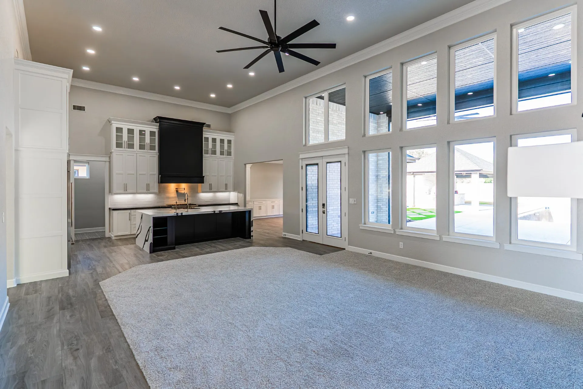 Great room at 27 Santiago Mission Dr with two stories of windows, French doors to the patio and an open view to the kitchen