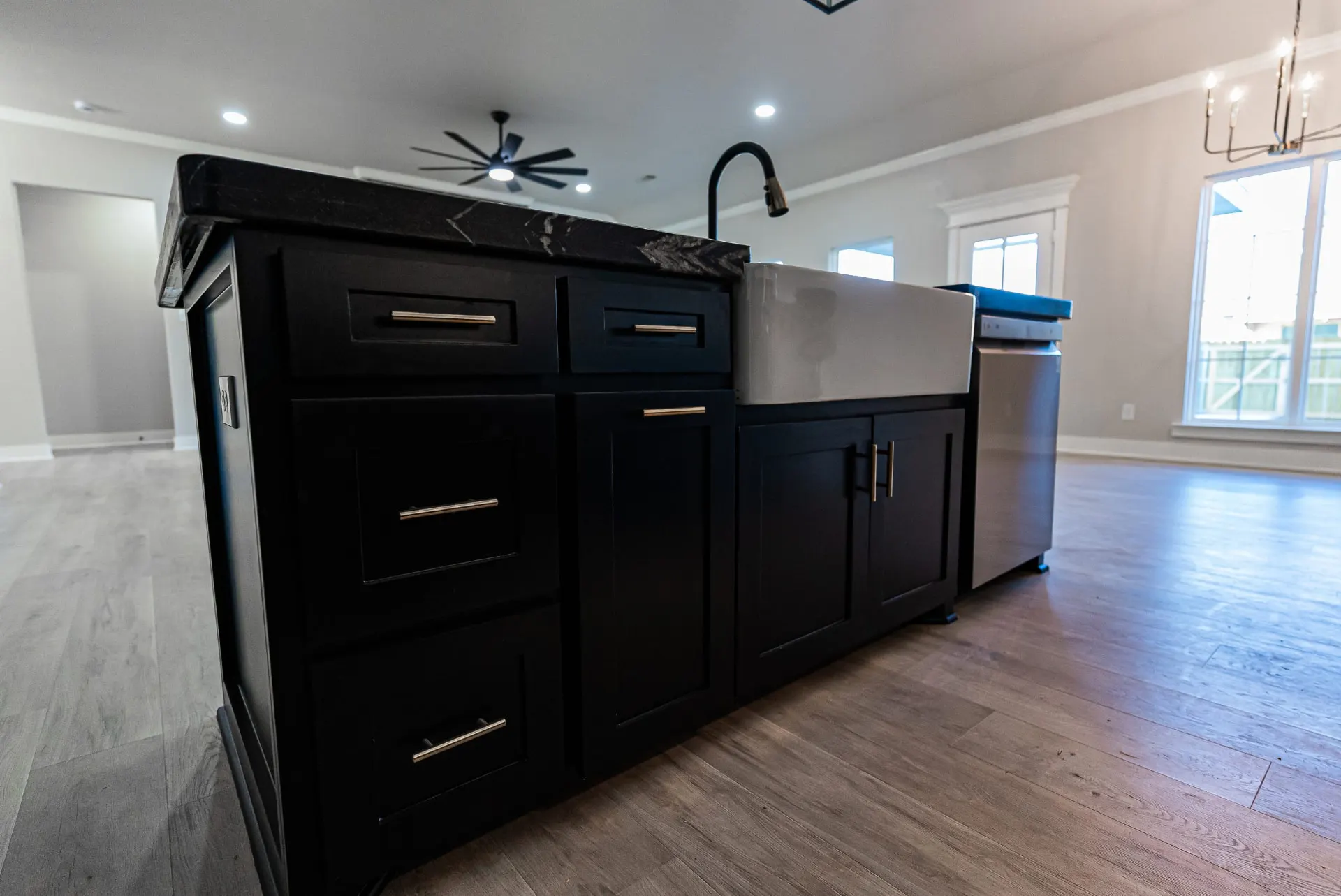Island detail at 708 K Ave with black shaker cabinetry, brass pulls and a farmhouse sink set in black marble