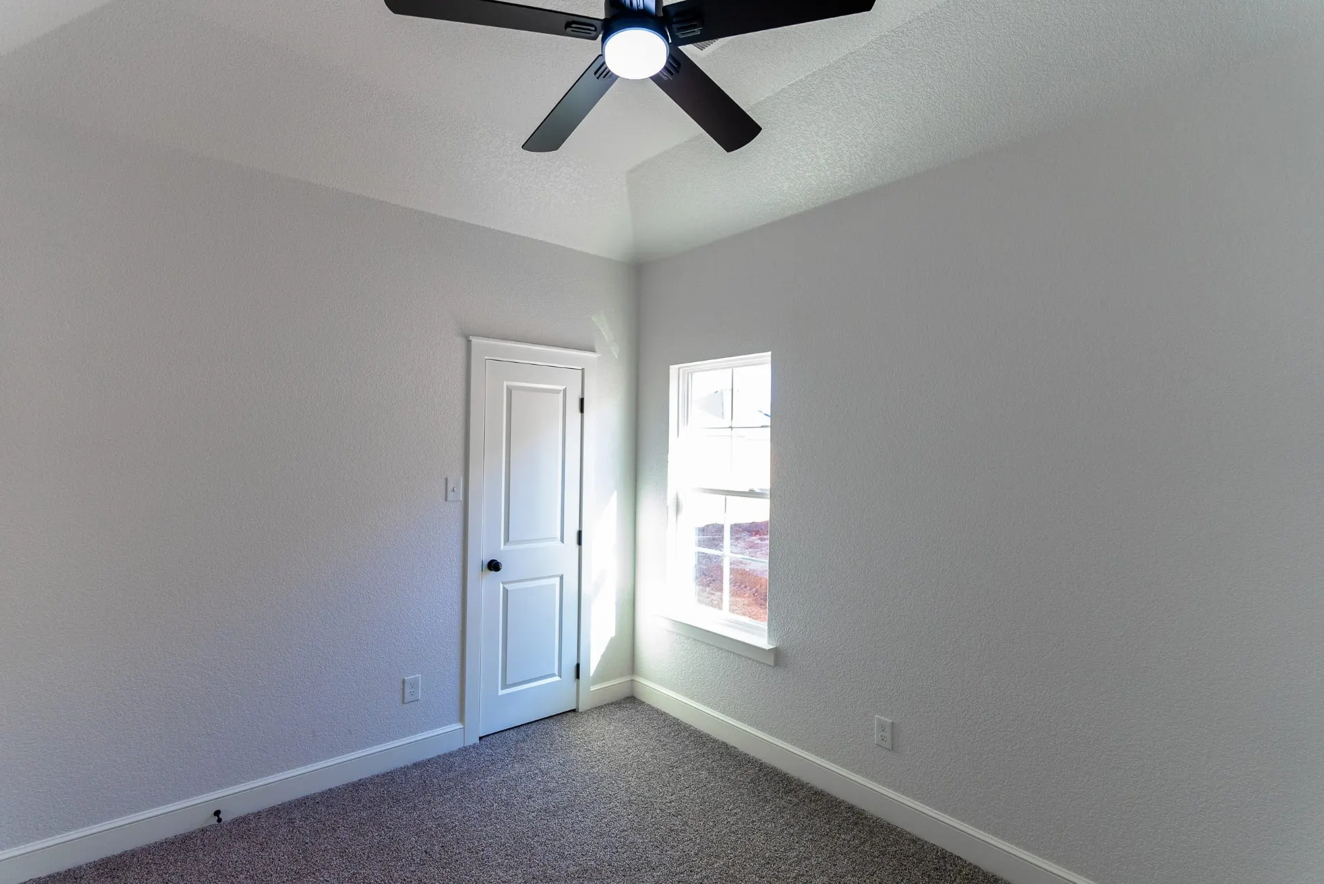 Bedroom at 718 K Ave with a tray ceiling, black ceiling fan, gray carpet and a sunlit window