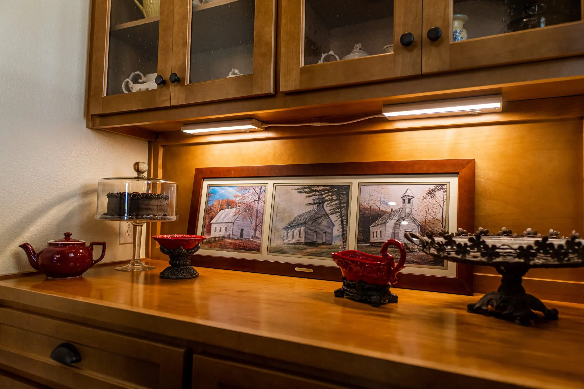 Built-in hutch at the Wraparound Porch Home with glass-front cabinets, under-cabinet lighting and a warm wood counter