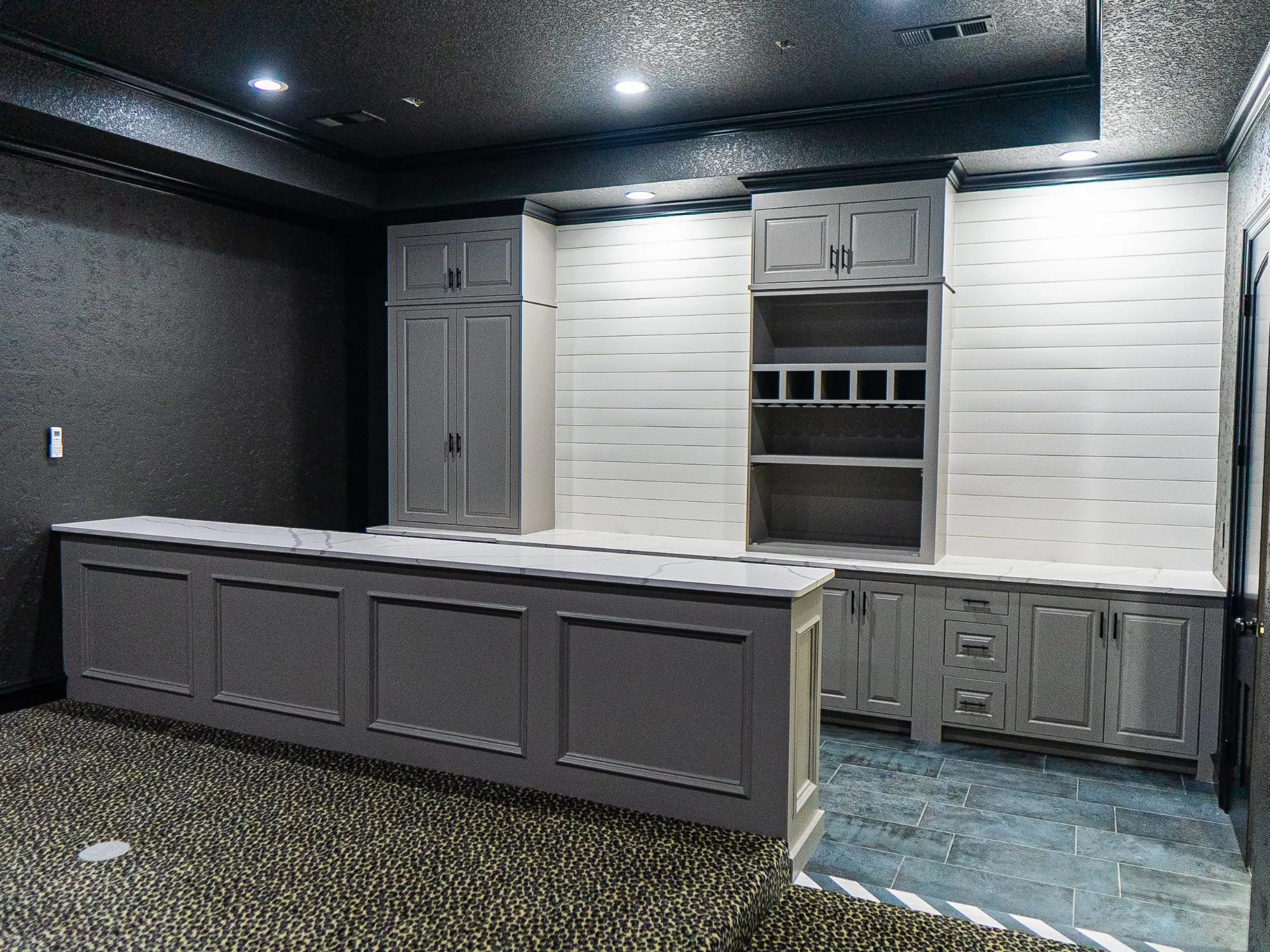 Theater room wet bar with gray cabinetry, wine cubbies and shiplap walls at 1501 NW 12th St