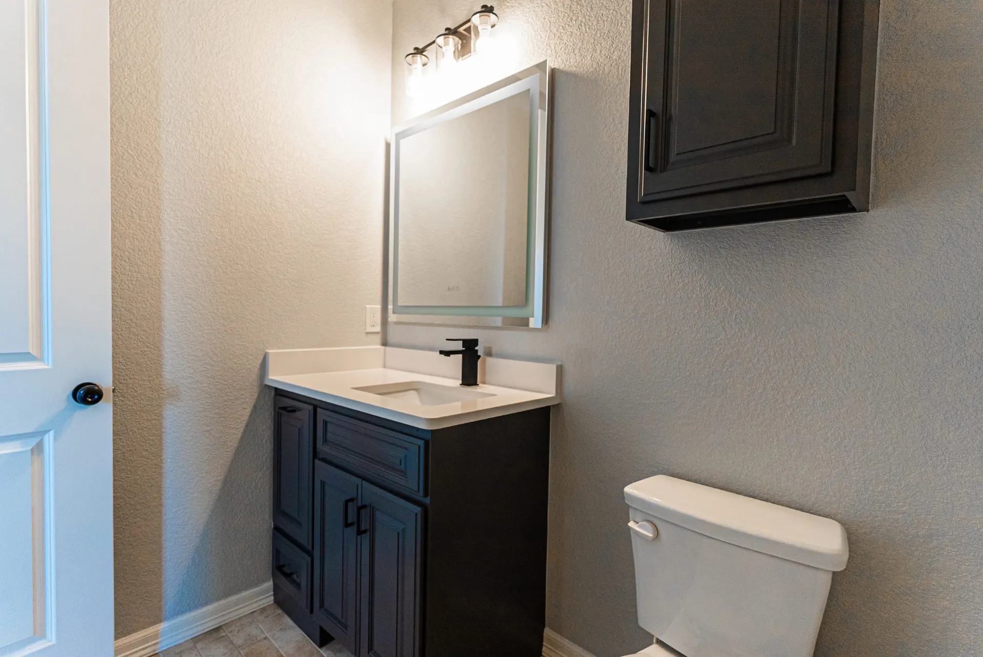 Powder room at 1511 NW 12th St with dark wood vanity, LED backlit mirror and matte-black faucet