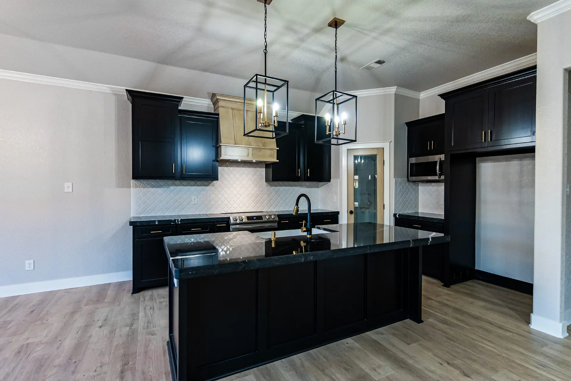 Kitchen at 708 K Ave with black cabinetry, brass hardware, twin lantern pendants and a black marble island
