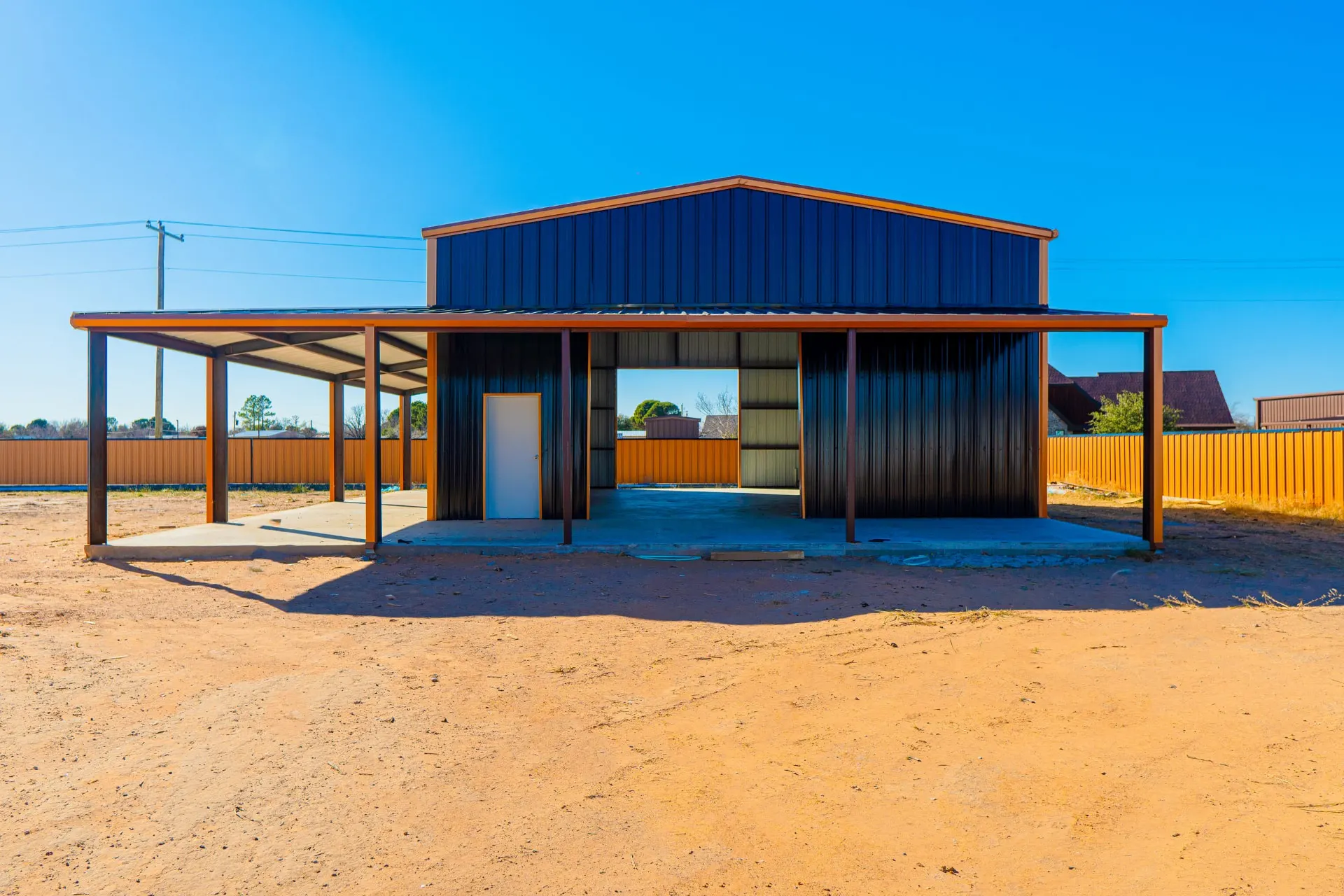 Front of the metal shop with a drive-through bay and covered lean-to wings at 8821 Shawn Dr