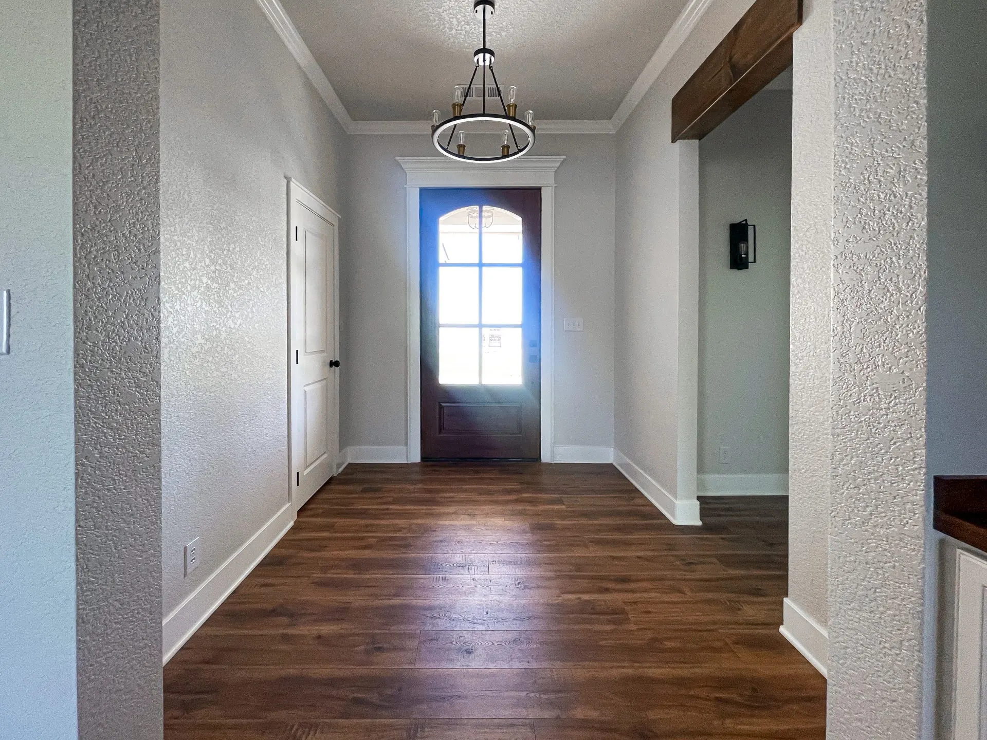 Entry at 1615 NW 12th St with arched-glass dark wood front door, ring chandelier, coffered ceiling and wood-look floors