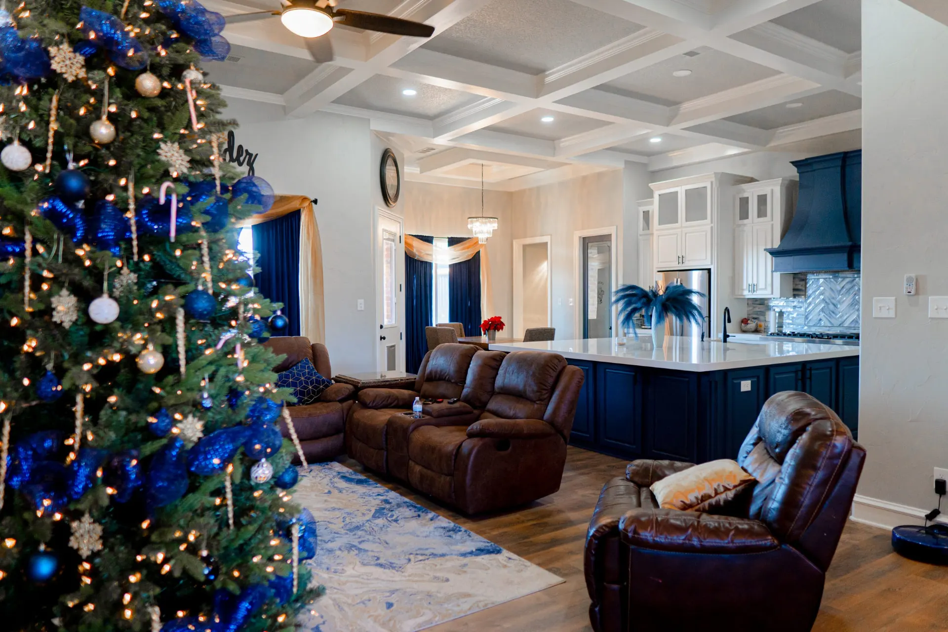 Living room at 8821 Shawn Dr opening to the navy-island kitchen under a white coffered ceiling, decorated for Christmas