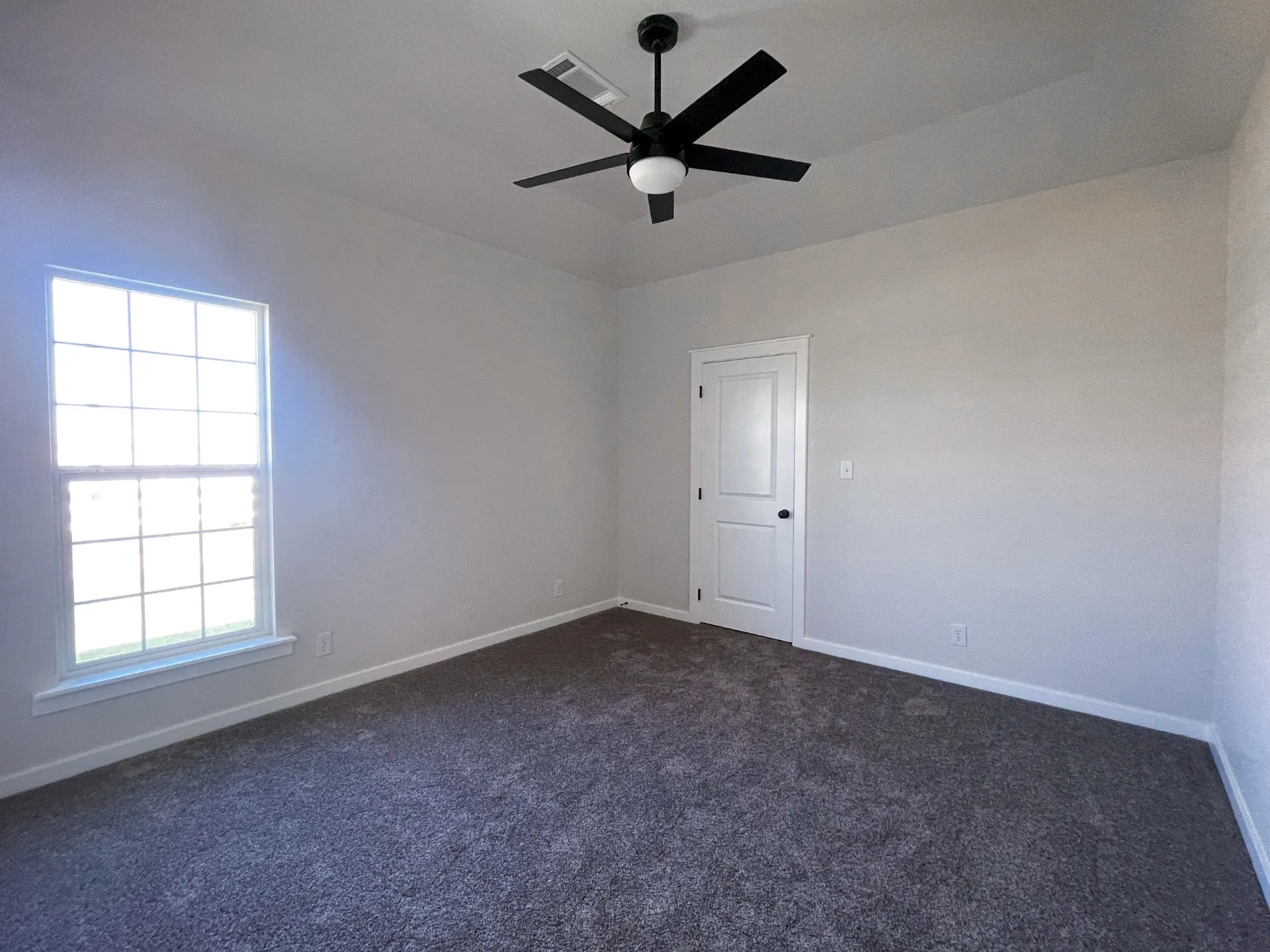 Bedroom at 1615 NW 12th St with dual windows, black ceiling fan, carpeted floors and white six-panel door