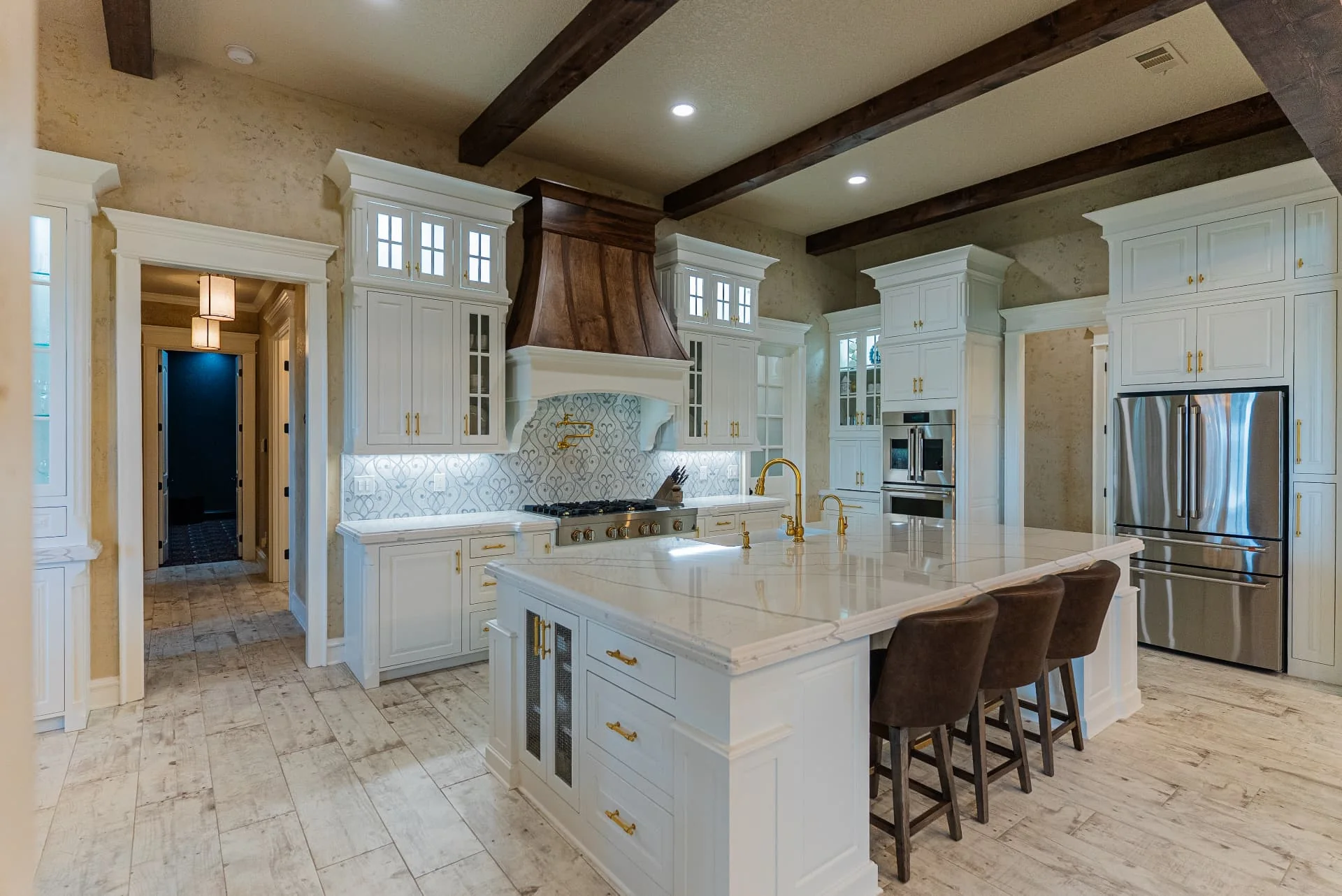 Kitchen at The Flores Estate with marble island, wood hood and white cabinetry