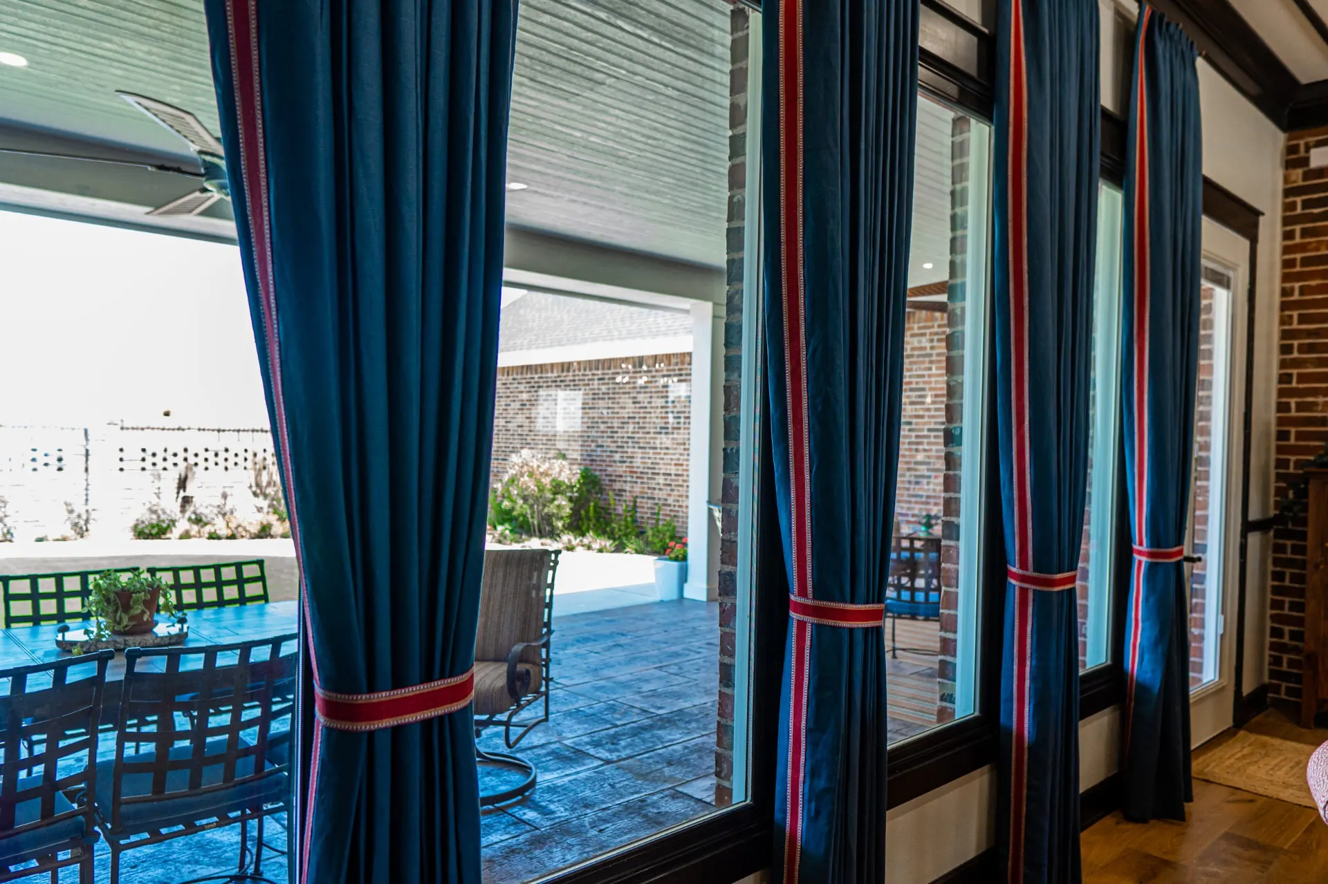 Tall windows at the Wraparound Porch Home with teal drapery looking out to the covered patio