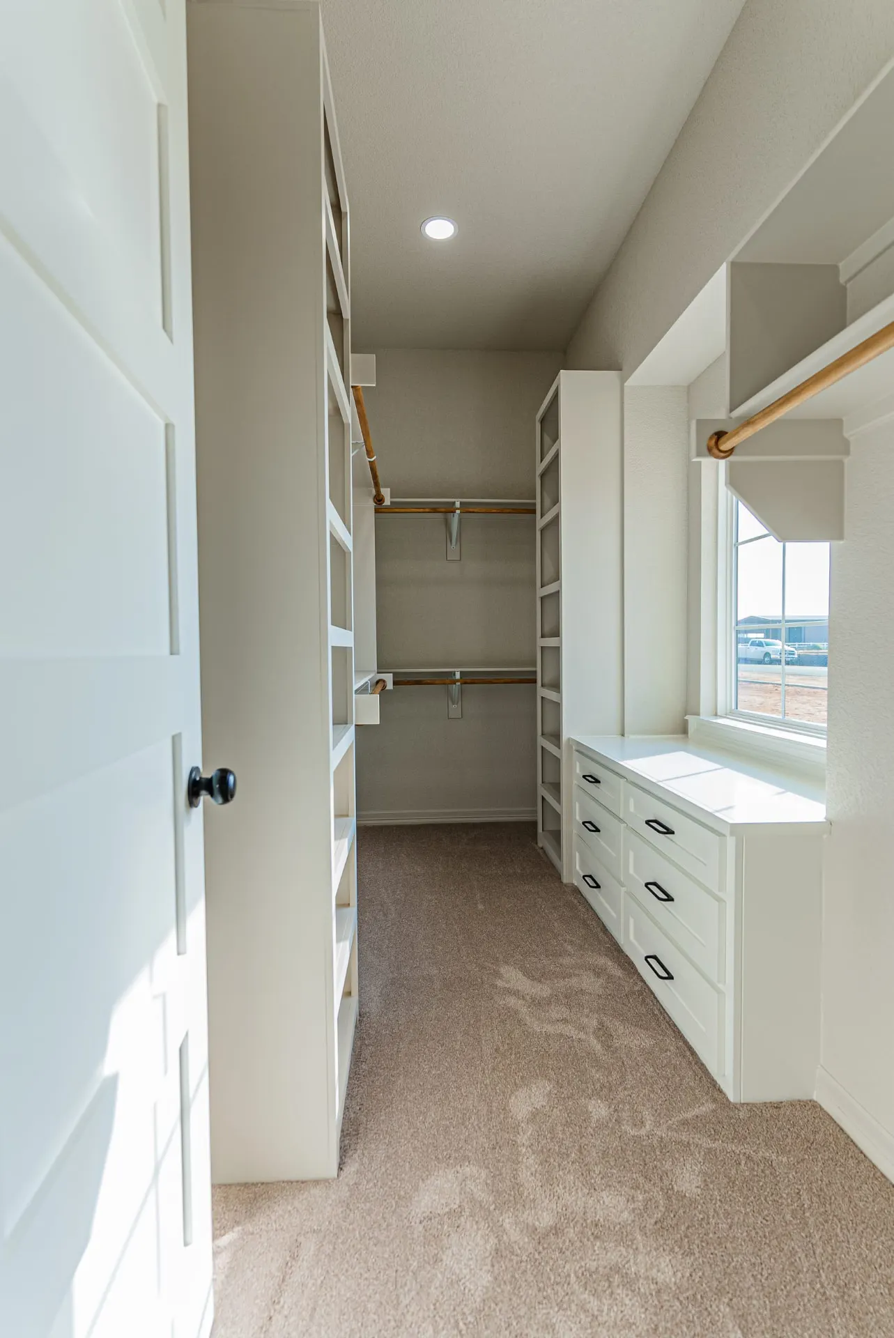 Walk-in closet at 1602 NW 12th St with white built-ins, wood hanging rods and window seat drawers