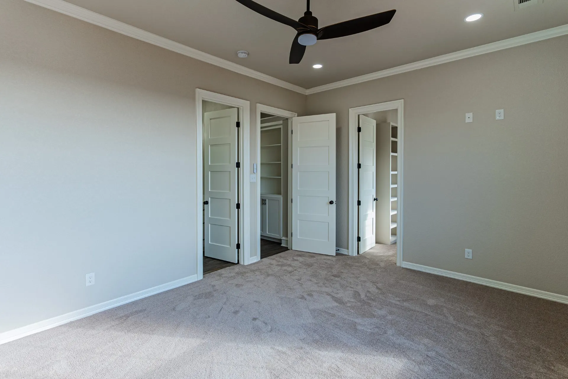 Carpeted bedroom at 1602 NW 12th St with black ceiling fan and doors to adjoining closets and bath