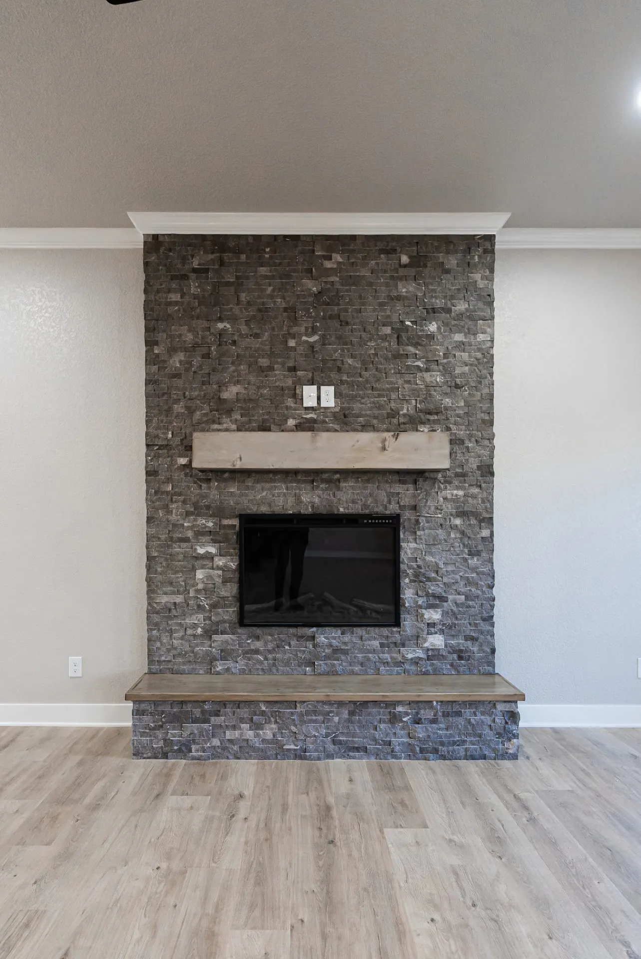 Floor-to-ceiling stacked-stone fireplace at 708 K Ave with a cedar mantel, raised stone hearth and light wood-look floors