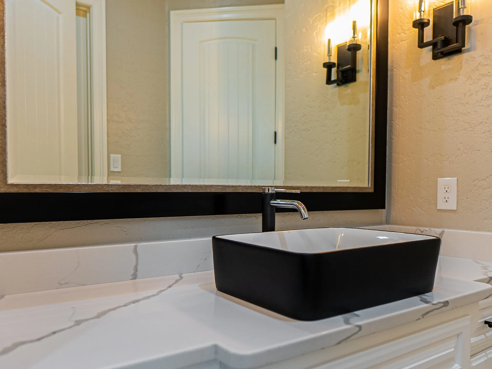 Bathroom vanity with a black vessel sink and bronze sconces at 1501 NW 12th St