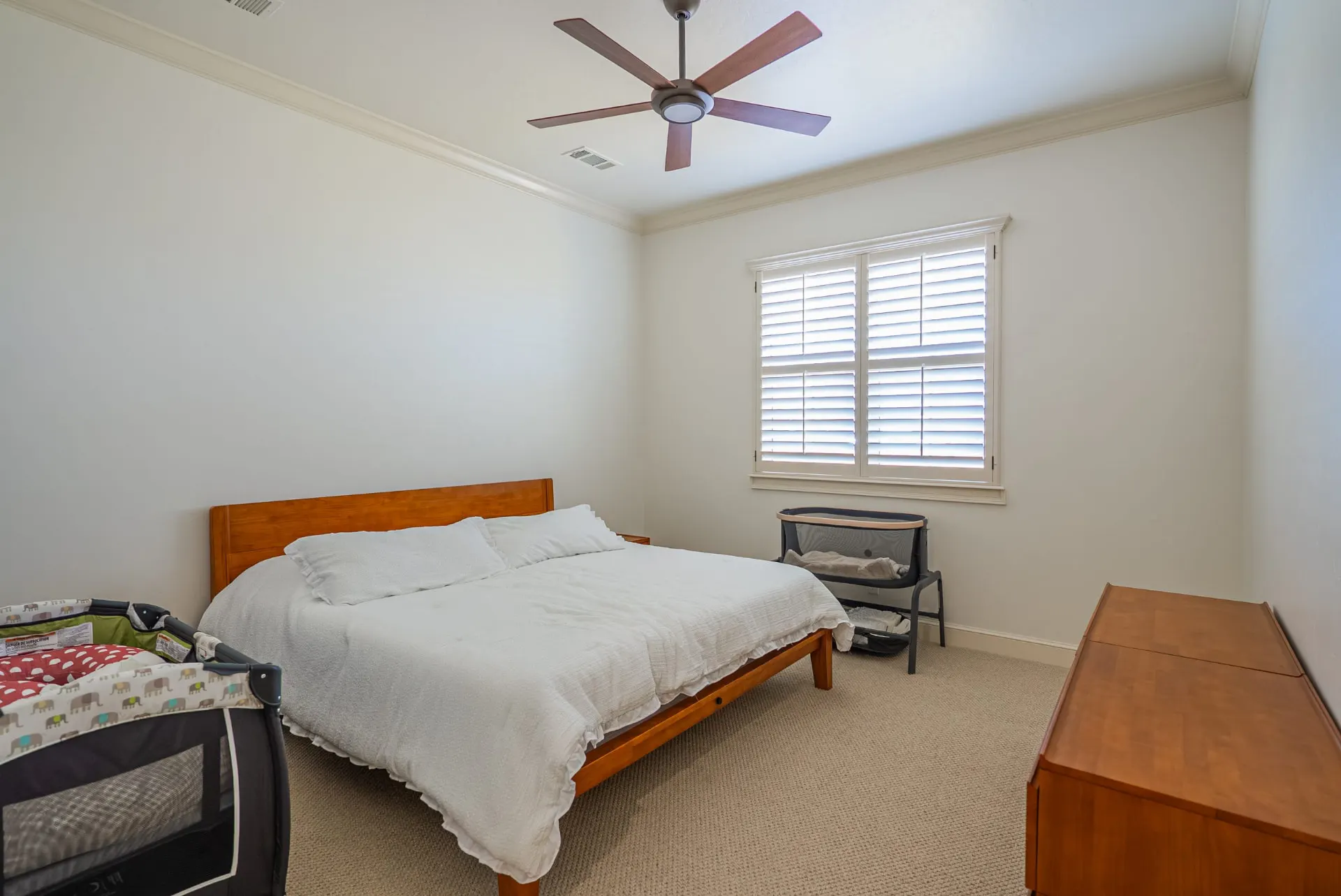 Guest bedroom at 1610 NW Eliam Dr with crown molding, ceiling fan and shuttered window