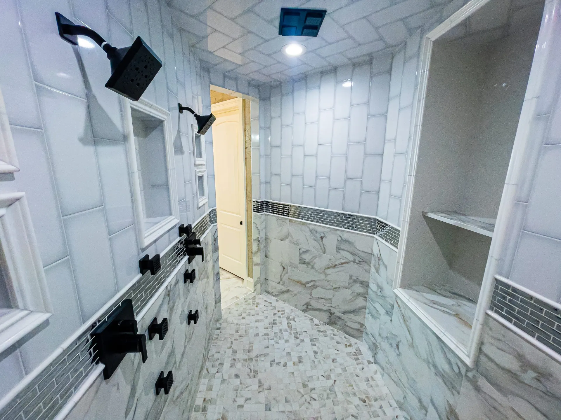 Walk-in shower with dual matte-black rain heads, marble-look tile and glass mosaic band at 1501 NW 12th St
