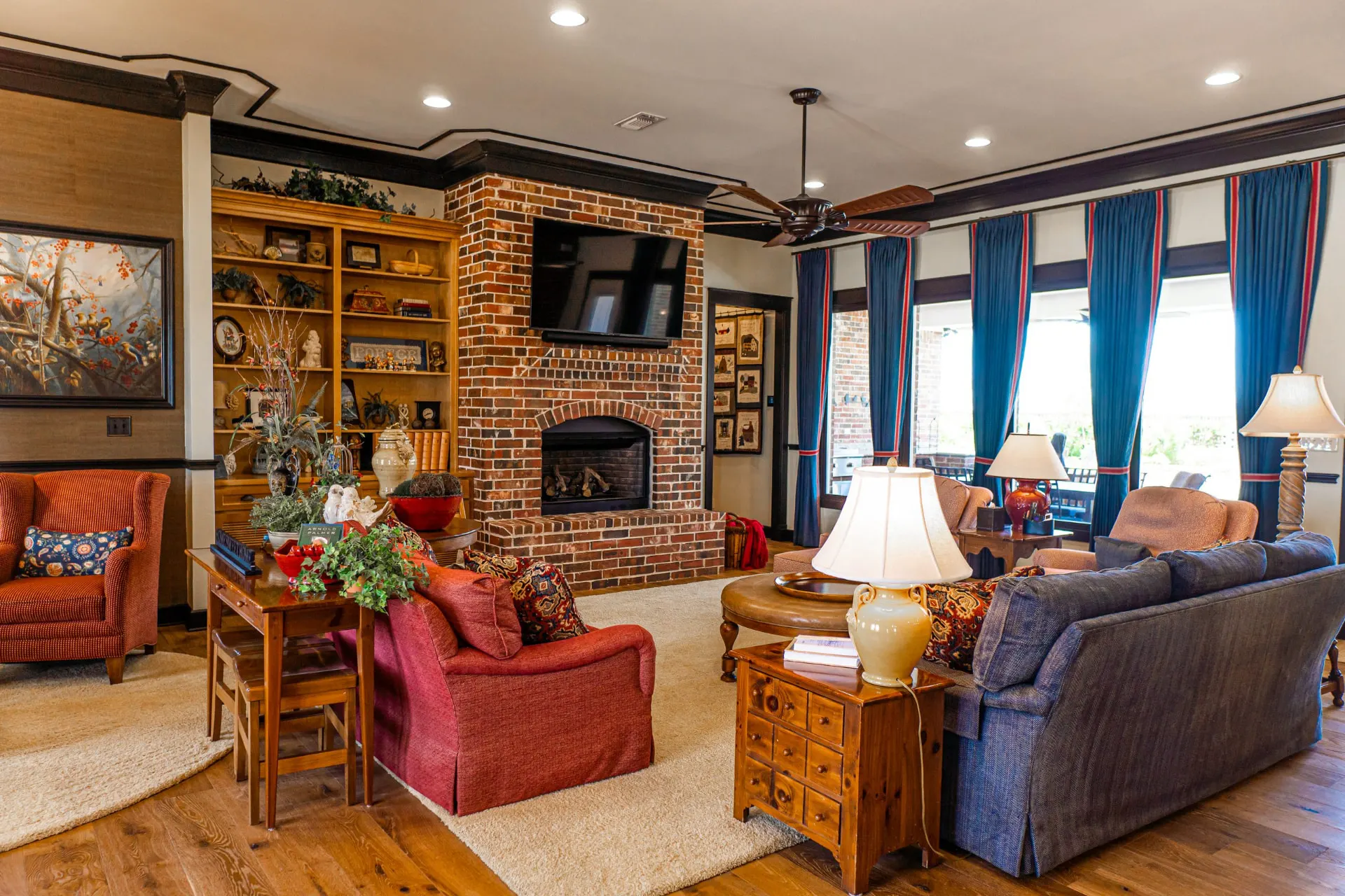 Living room at the Wraparound Porch Home with a red brick fireplace, wall-mounted television, navy sofa and full-height built-in bookshelves