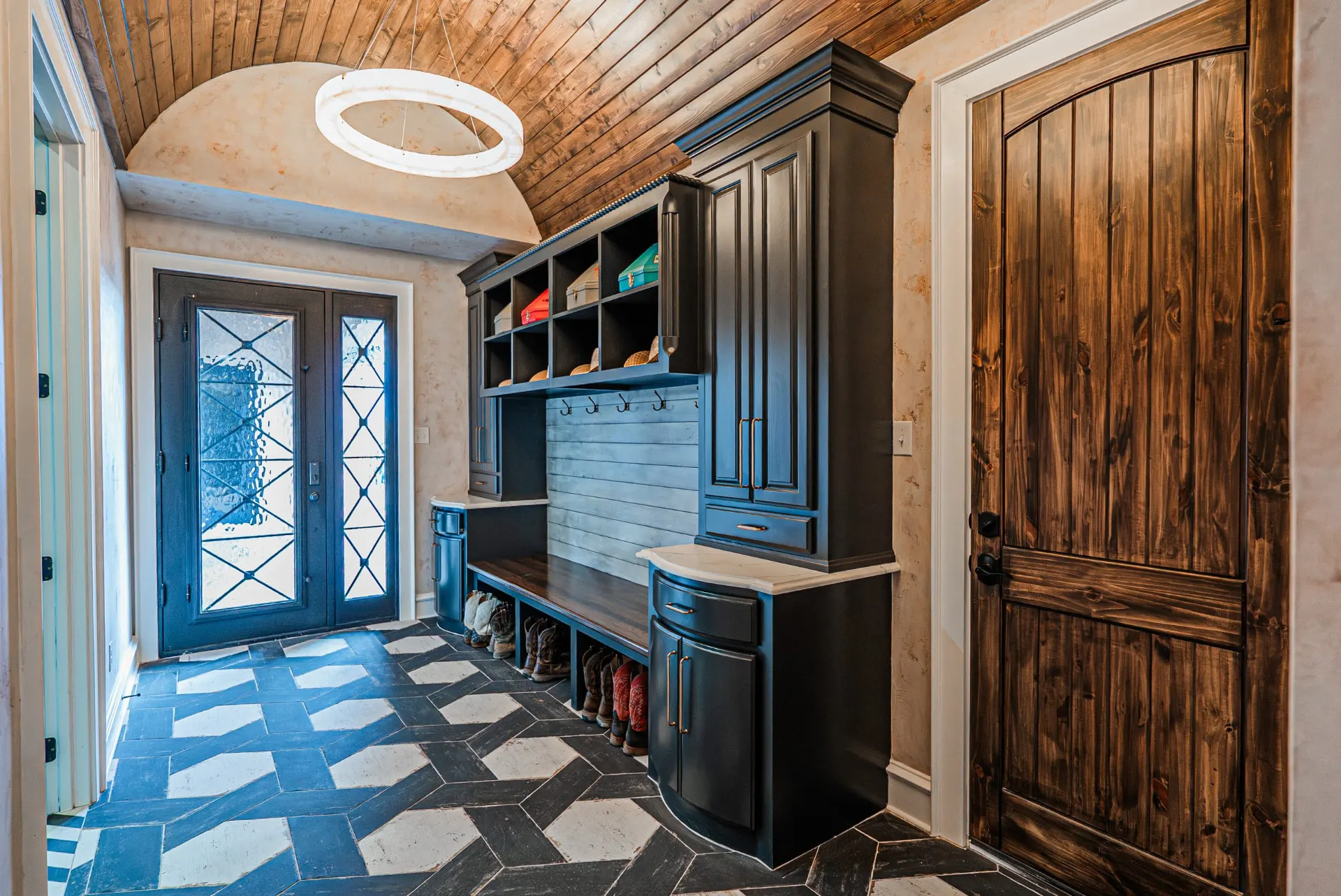 Mudroom at 5 Prairie Ln with black lockers, hat cubbies and herringbone tile floor