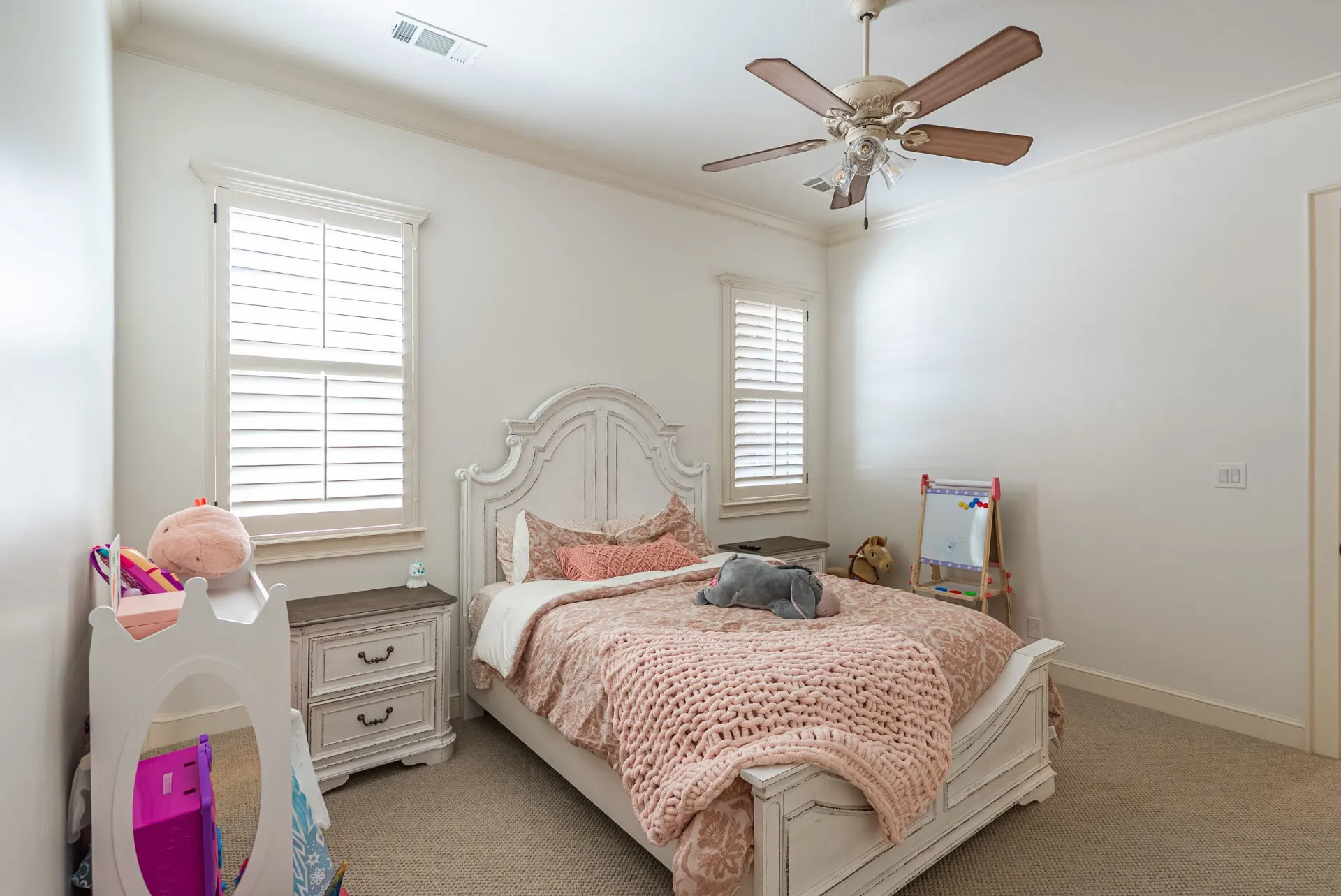 Secondary bedroom at 1610 NW Eliam Dr with crown molding and plantation shutters