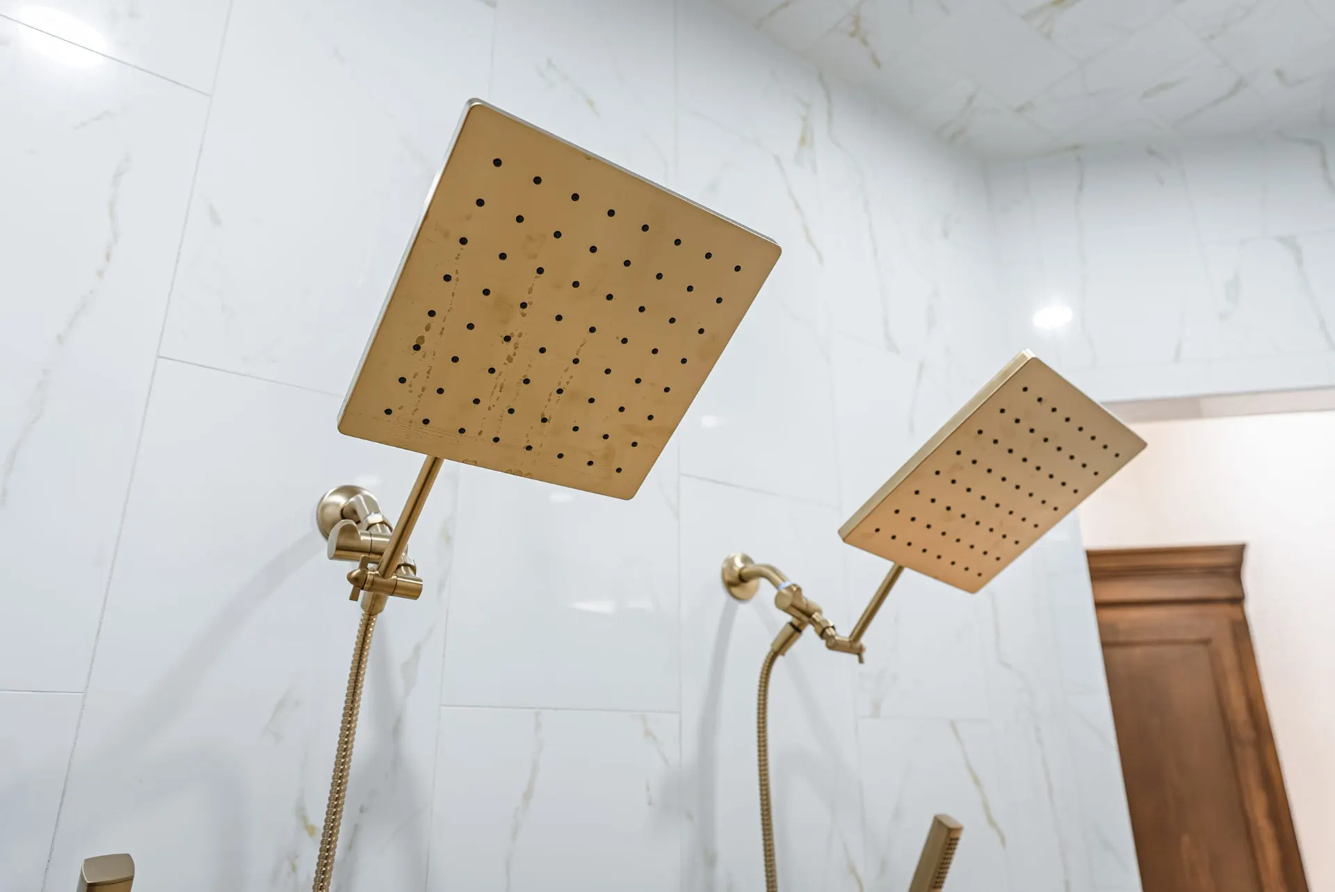 Brushed brass showerheads against gold-veined white tile at 1607 NW 12th St