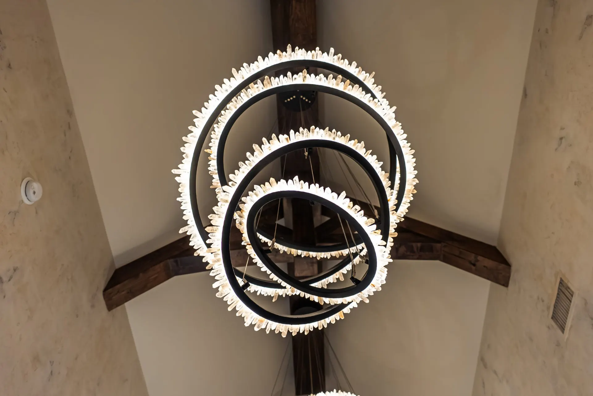Crystal ring chandelier at 5 Prairie Ln under exposed ceiling beams